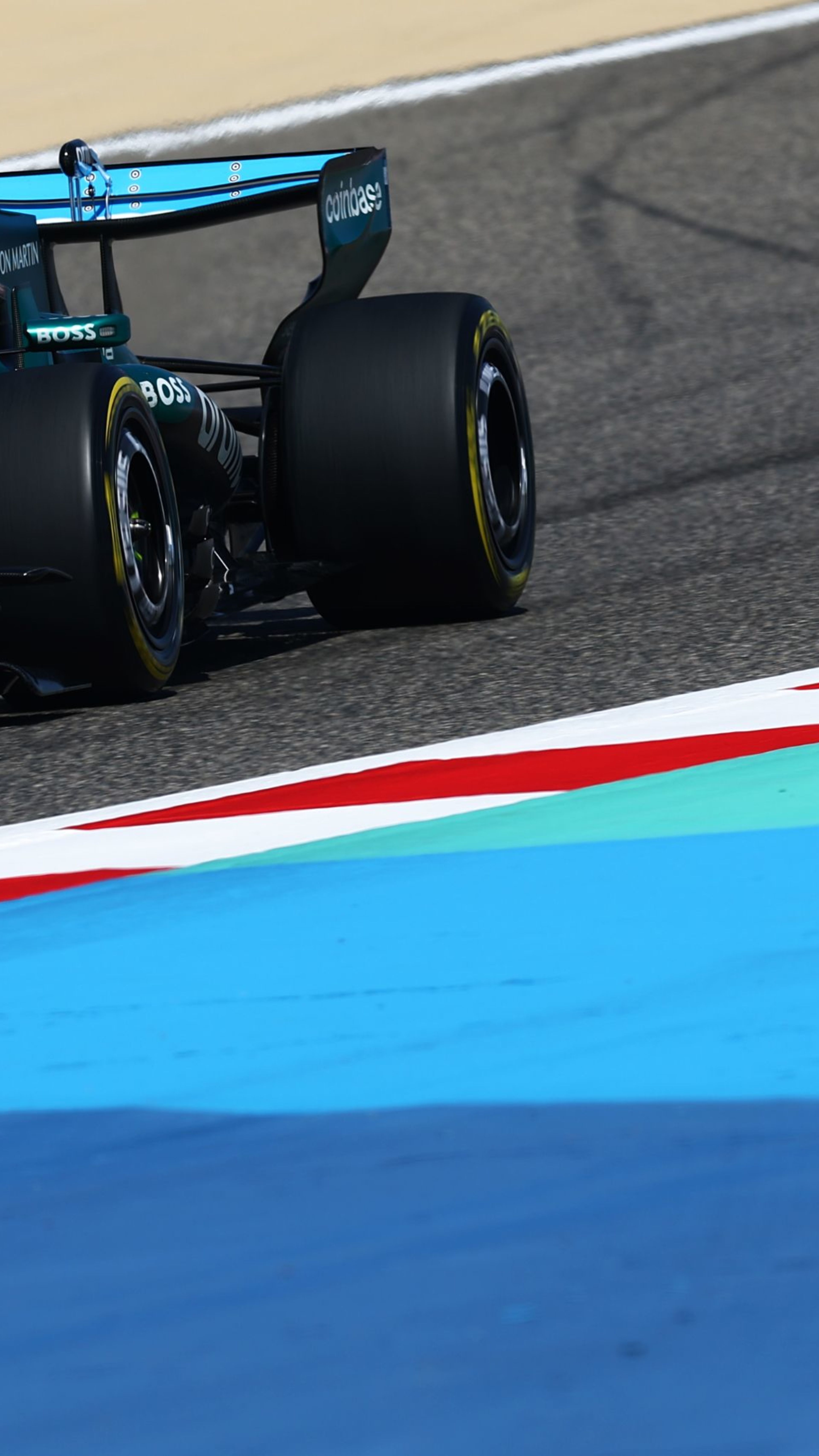 A teal and black Aston Martin F1 car with the number 18 speeds along a racetrack.