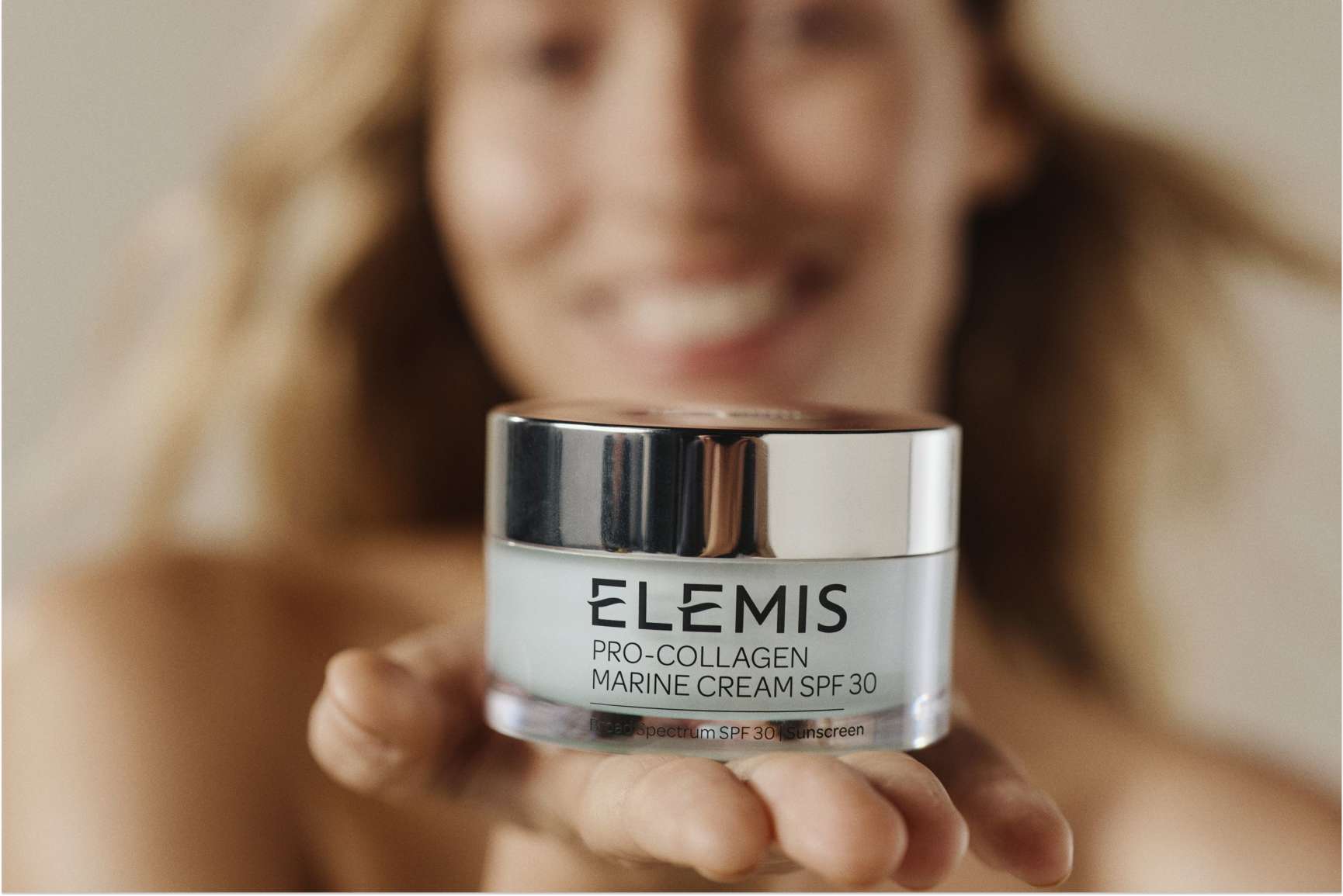 A person holds a jar of Elemis Pro-Collagen Marine Cream SPF 30.