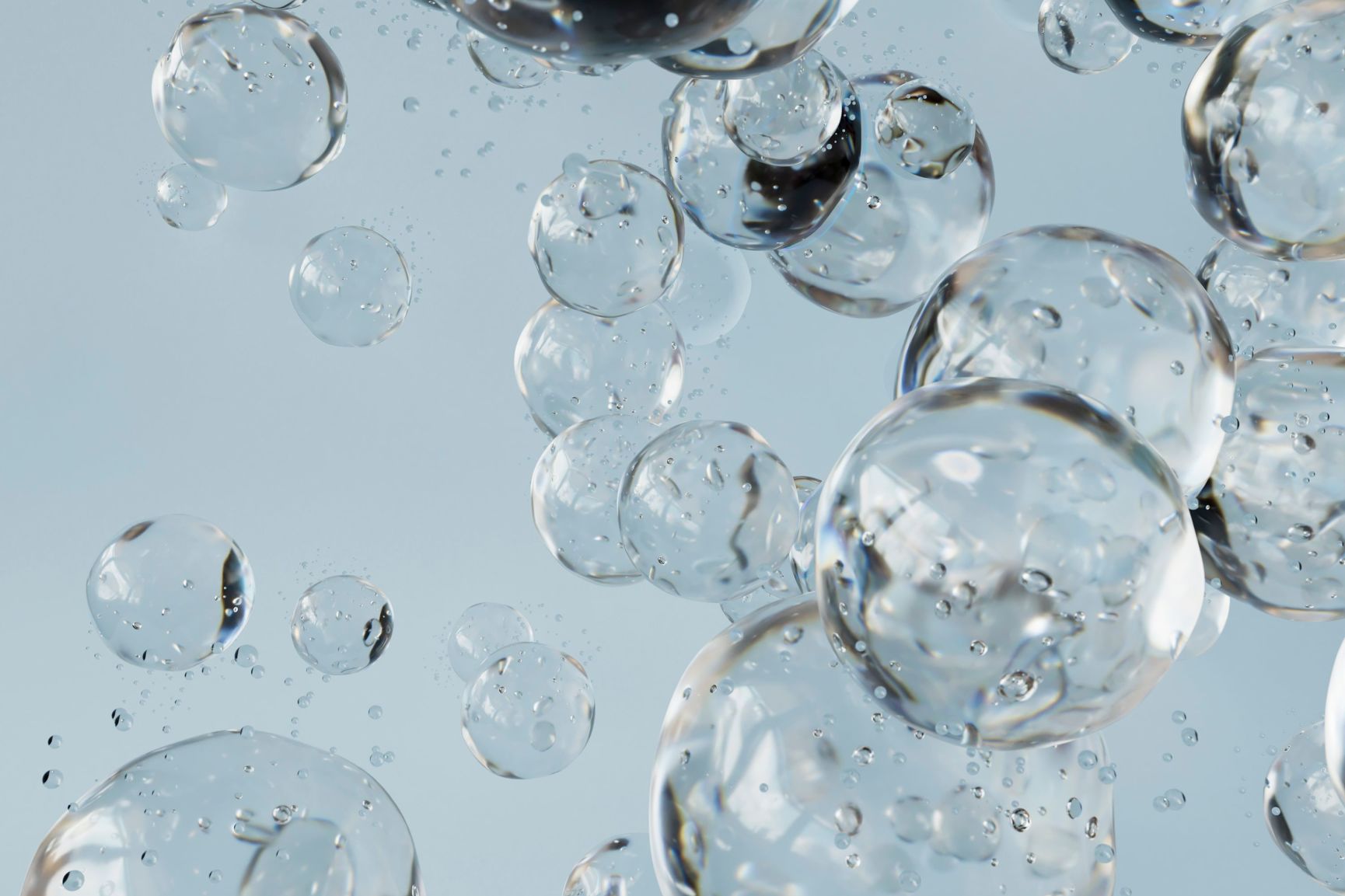 Bubbles of various sizes suspended in a clear liquid against a light background.