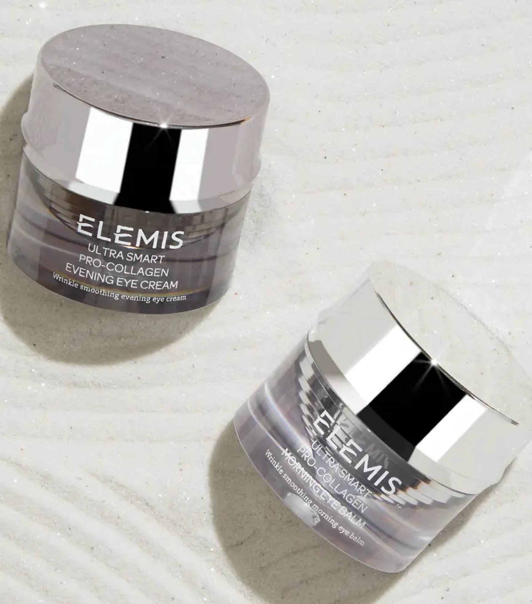 Two Elemis Ultra Smart Pro-Collagen eye cream jars, one for morning and one for evening, on a glittery surface.