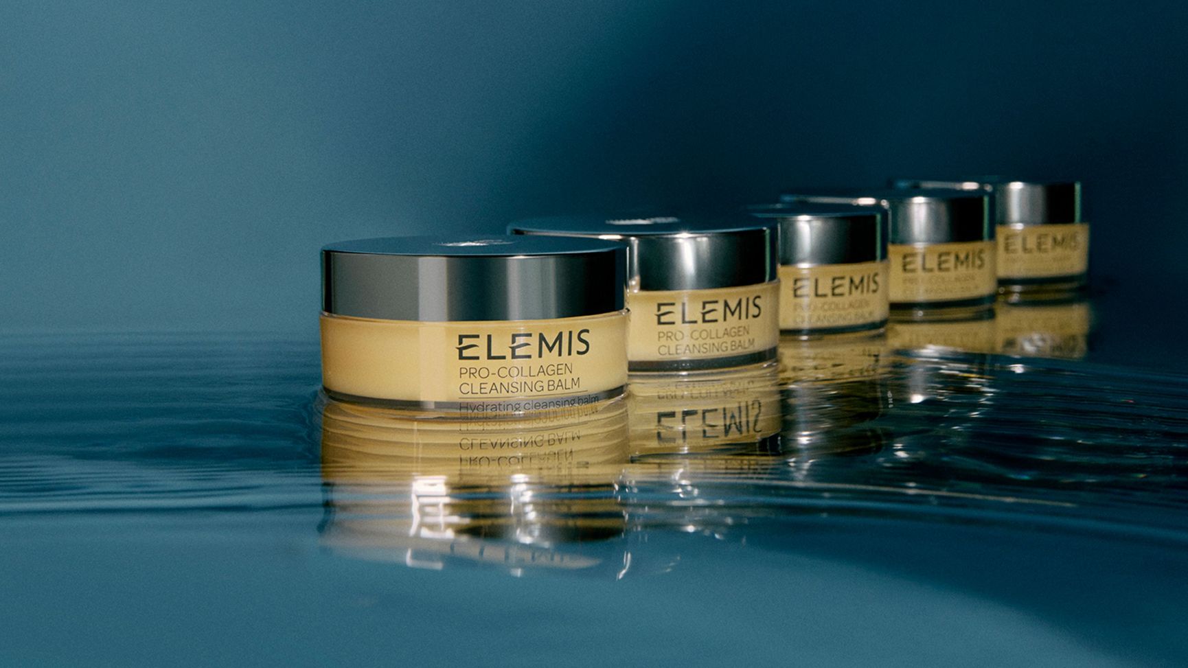 Woman holding an open jar of Elemis Pro-Collagen Cleansing Balm.