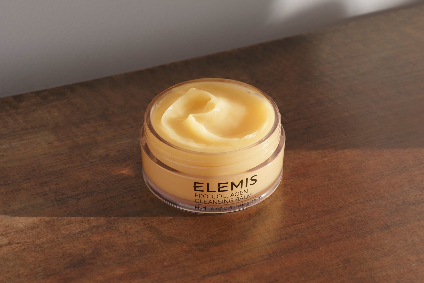 Cleansing Balm with the lid open sitting on a wooden table