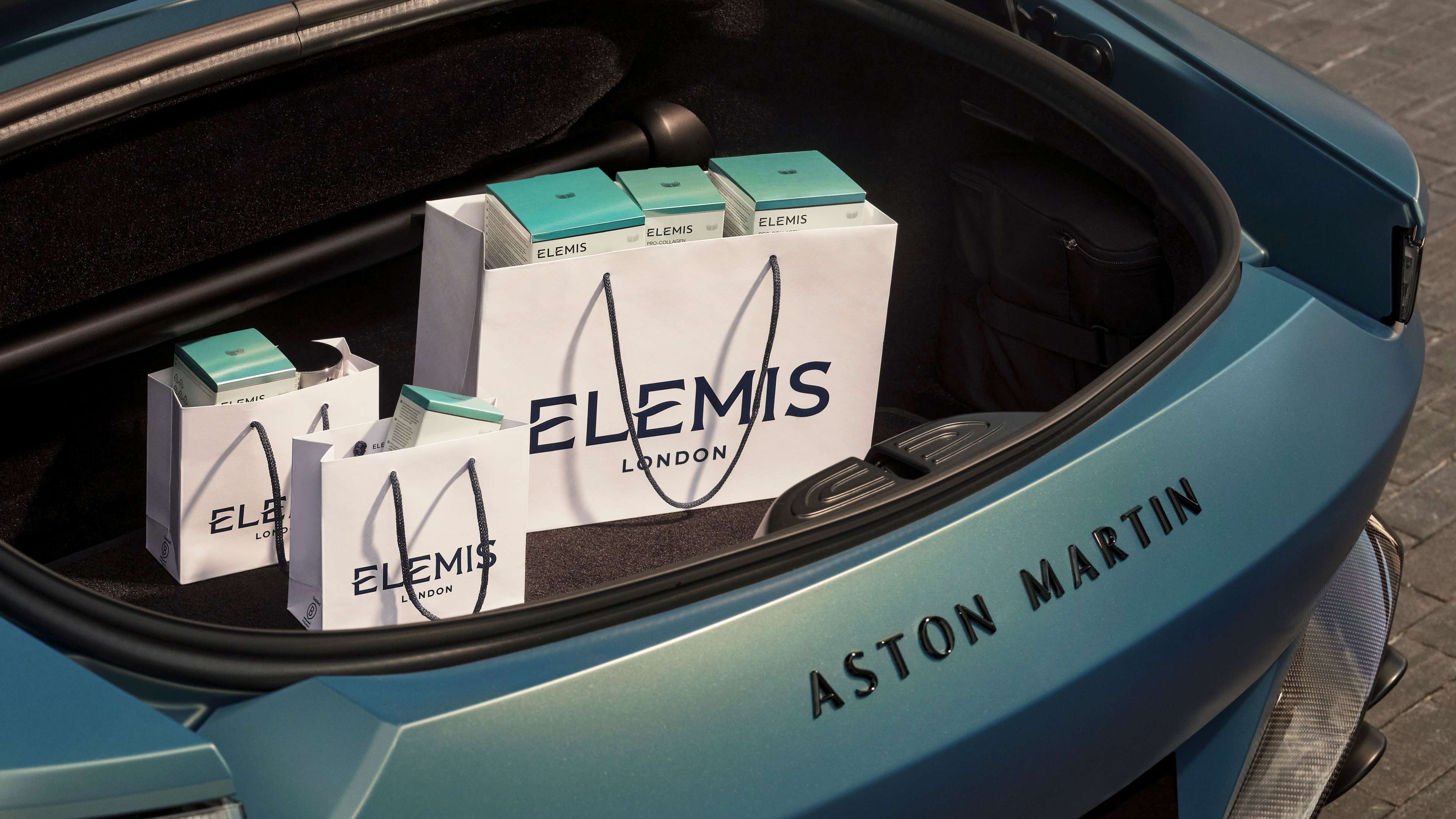 Three Elemis skincare products stacked on a reflective blue surface.