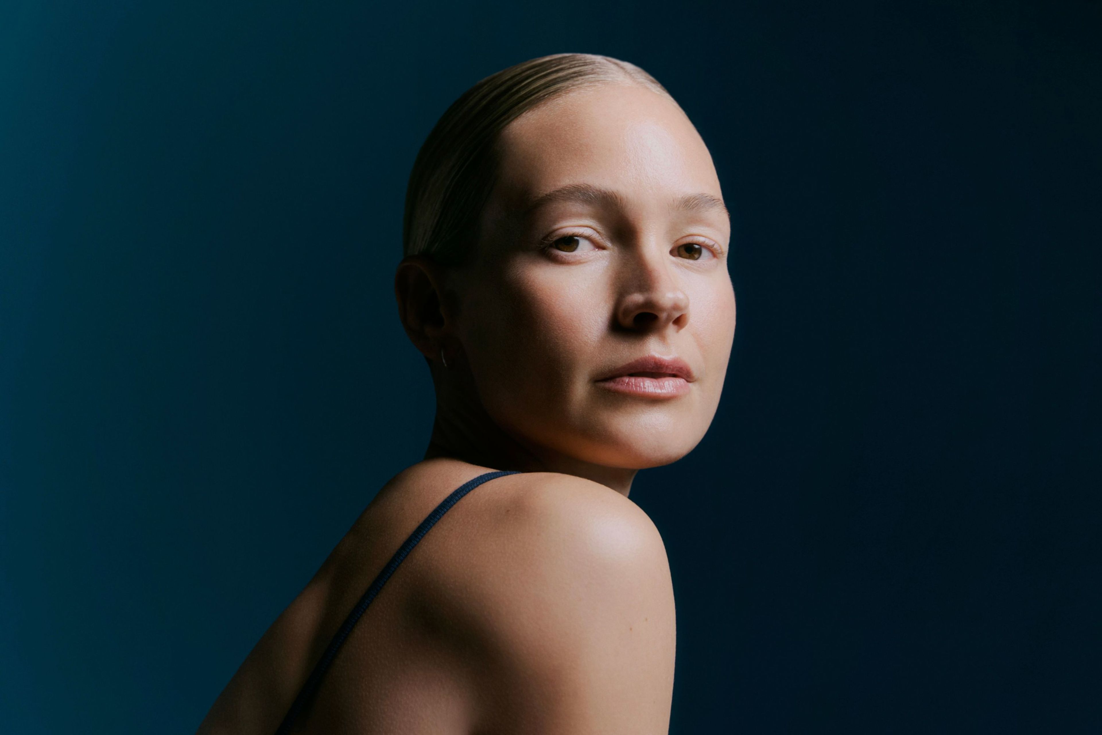 Woman sitting in dark room with light from above