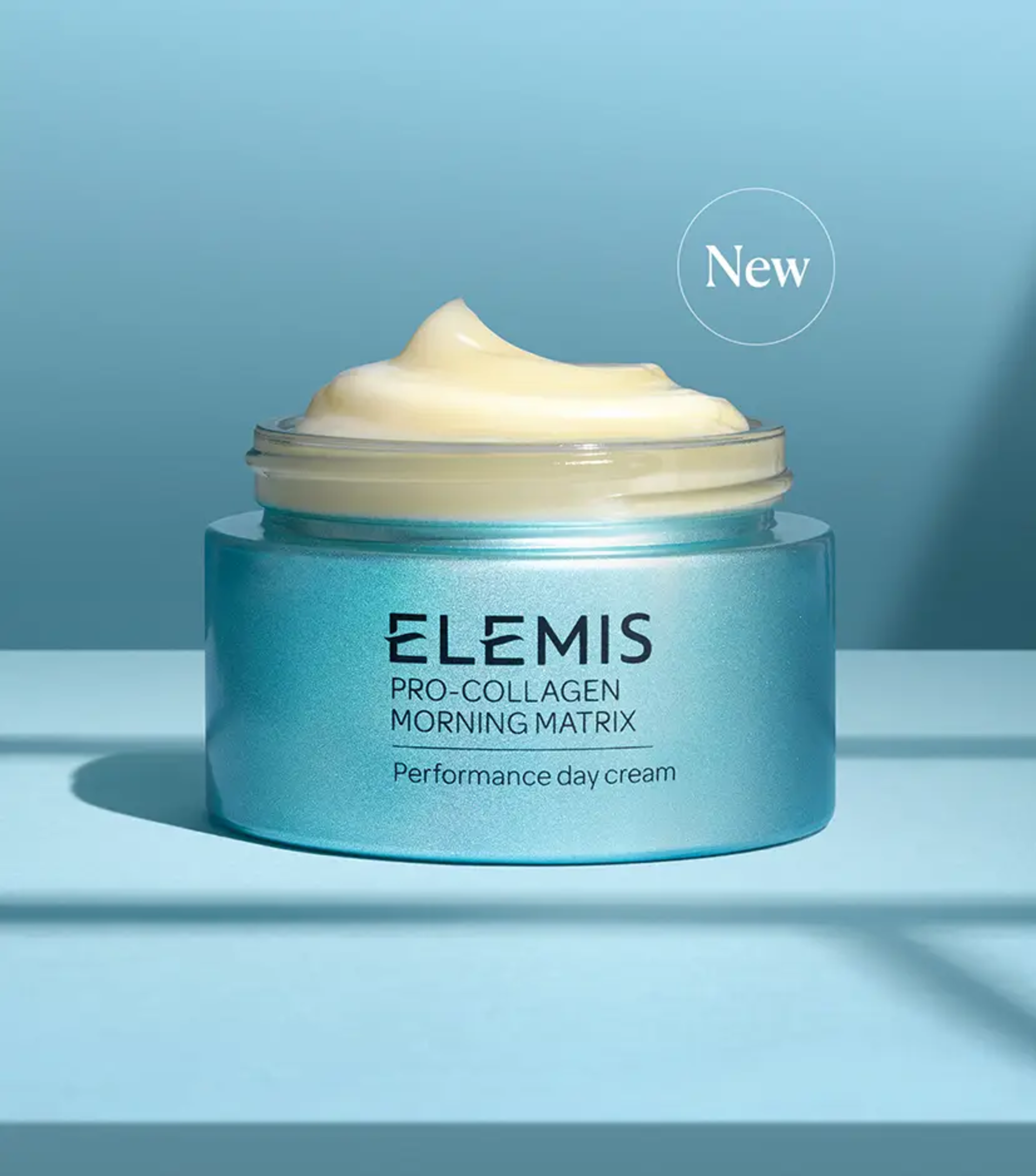 Open, shimmery blue-green jar of Elemis Pro-Collagen Morning Matrix Performance Day Cream with a "New" label.