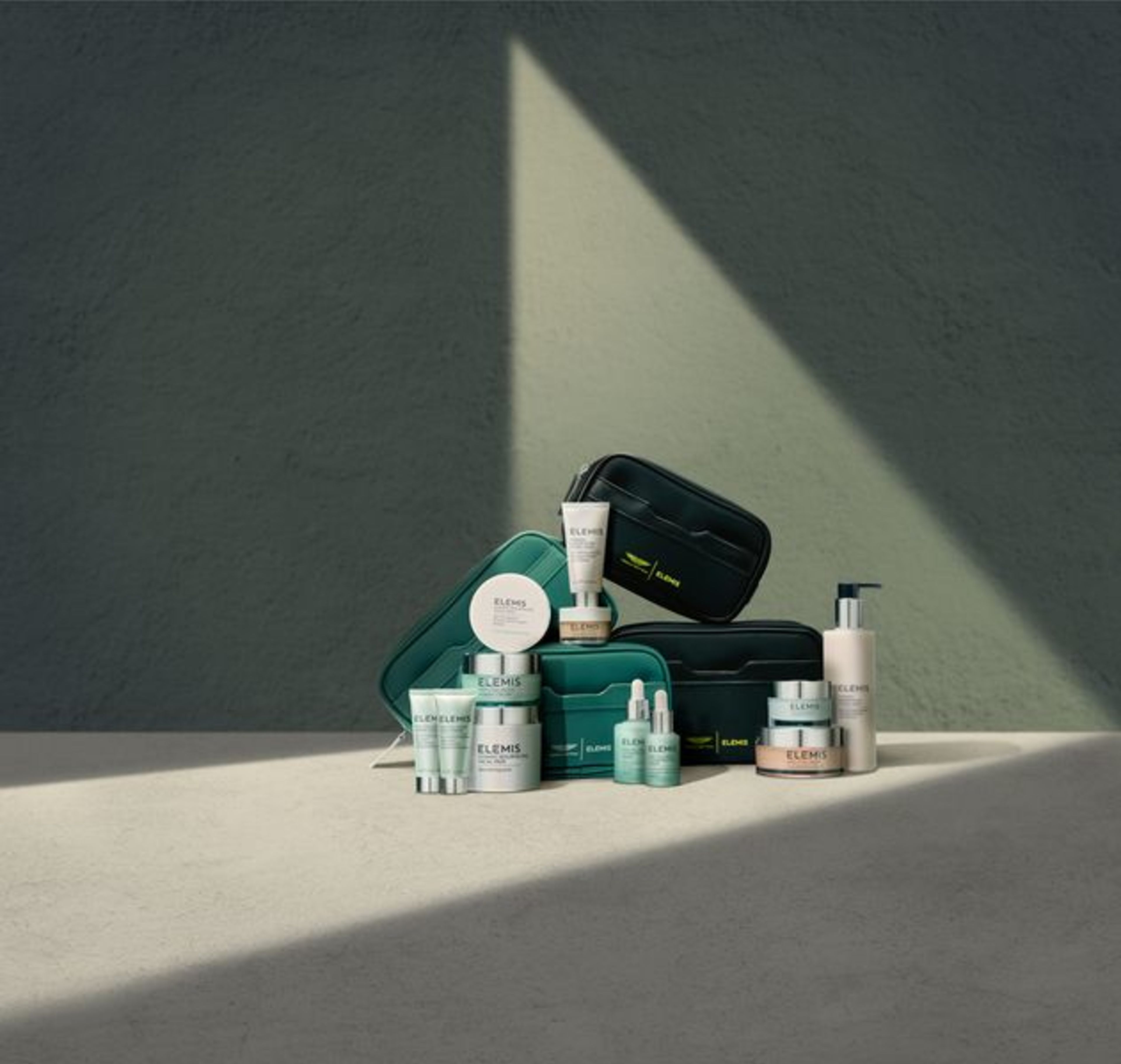 Elemis skincare products and teal and black travel bags, some featuring an Aston Martin logo.