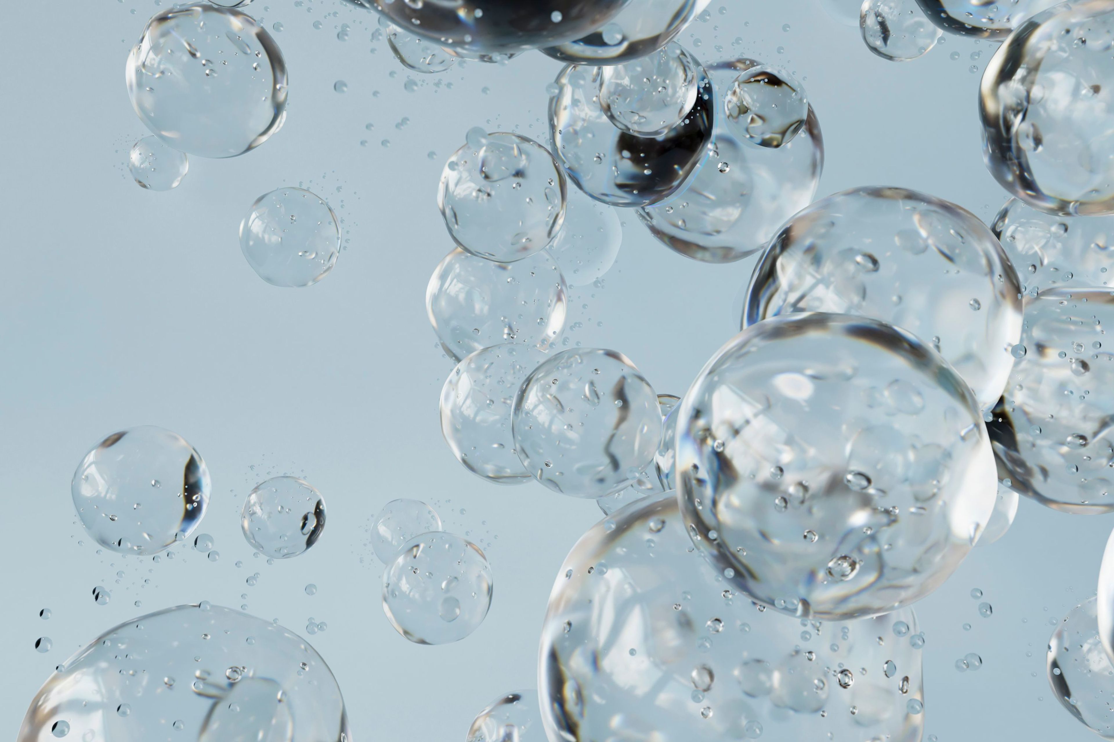 Bubbles of various sizes suspended in a clear liquid against a light background.