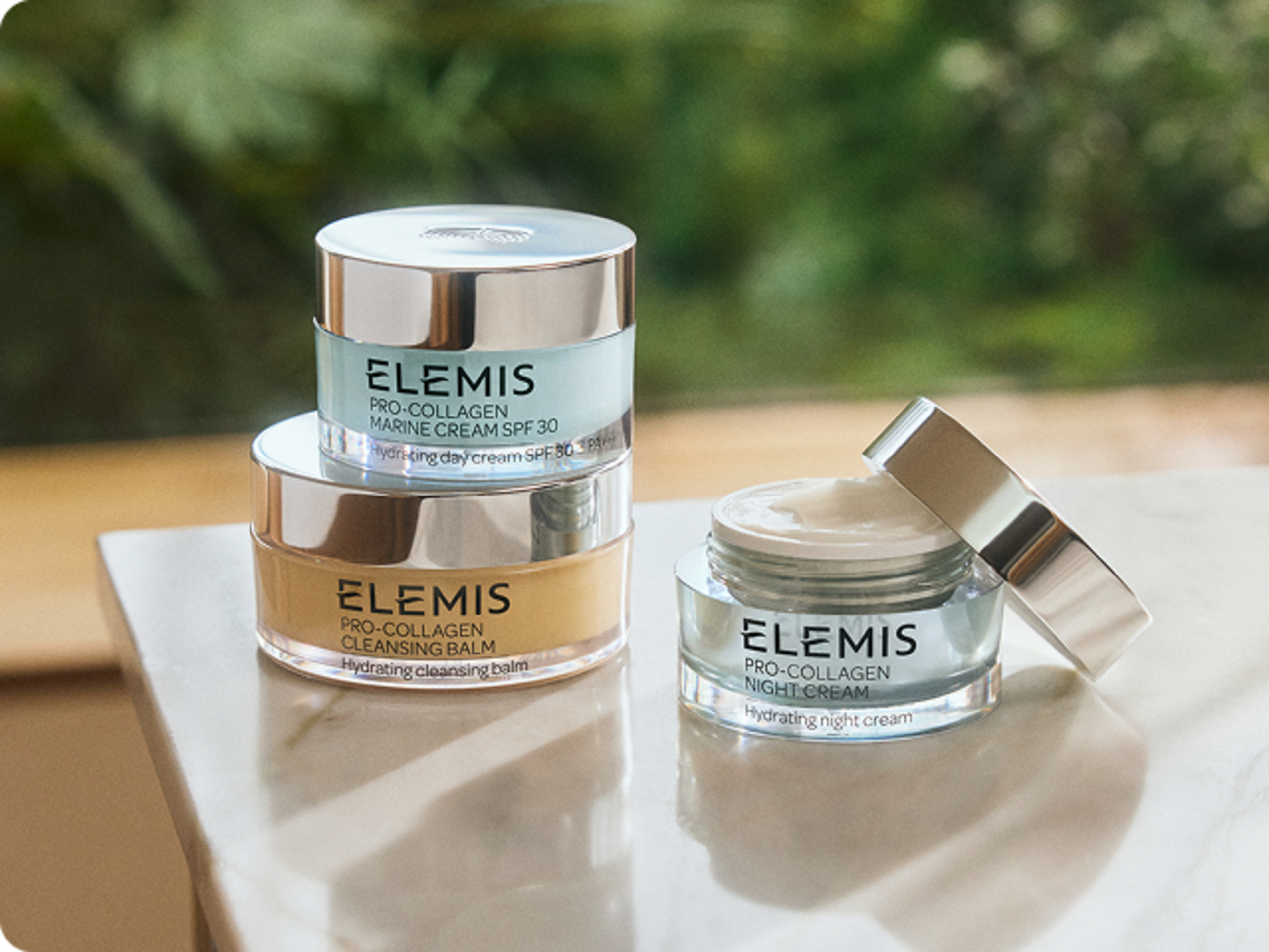 Elemis Pro-Collagen Cleansing Balm, Toning Mist, and Marine Cream on a bathroom counter.