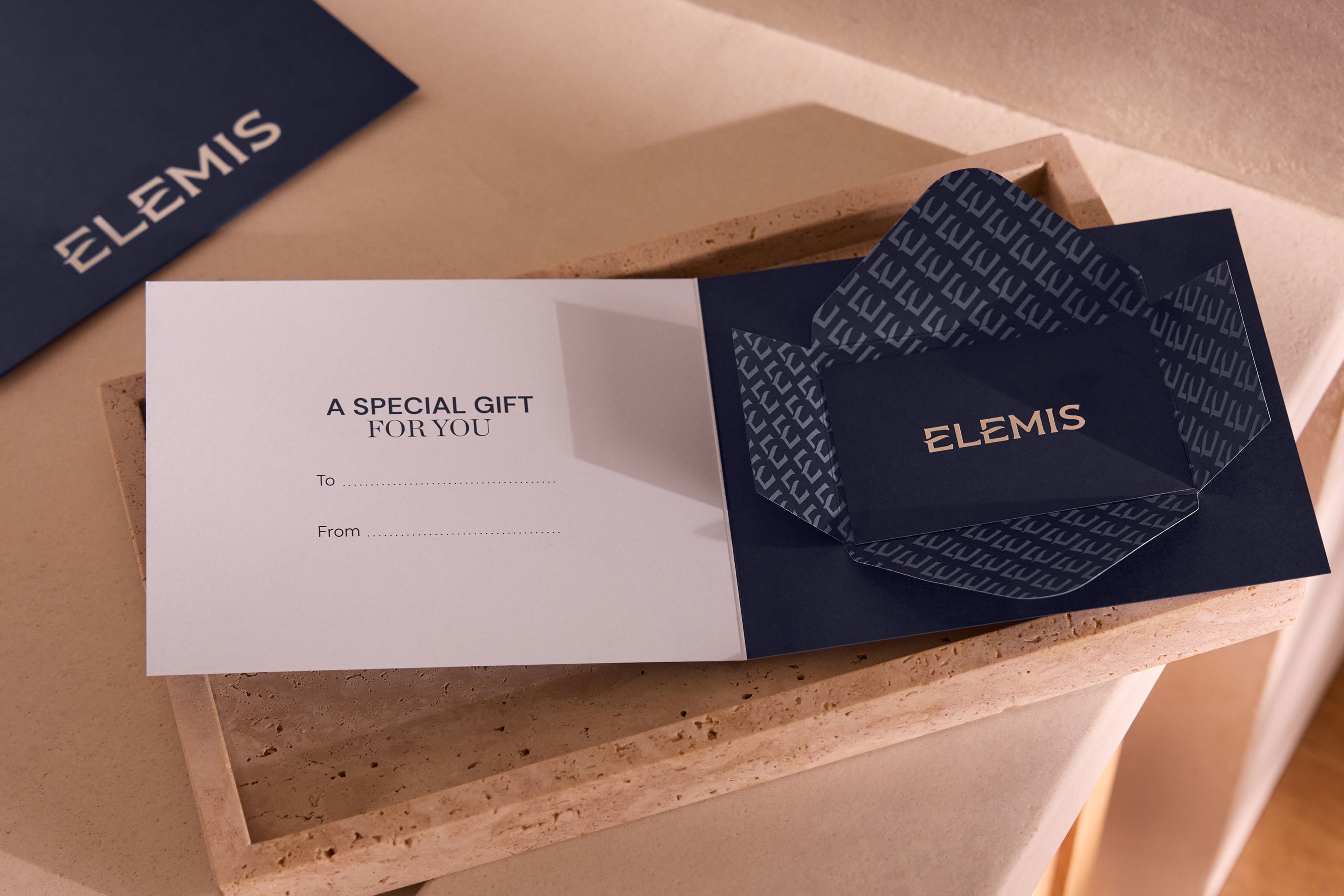 Hands dipping a finger into an open jar of Elemis Pro-Collagen Marine Cream.