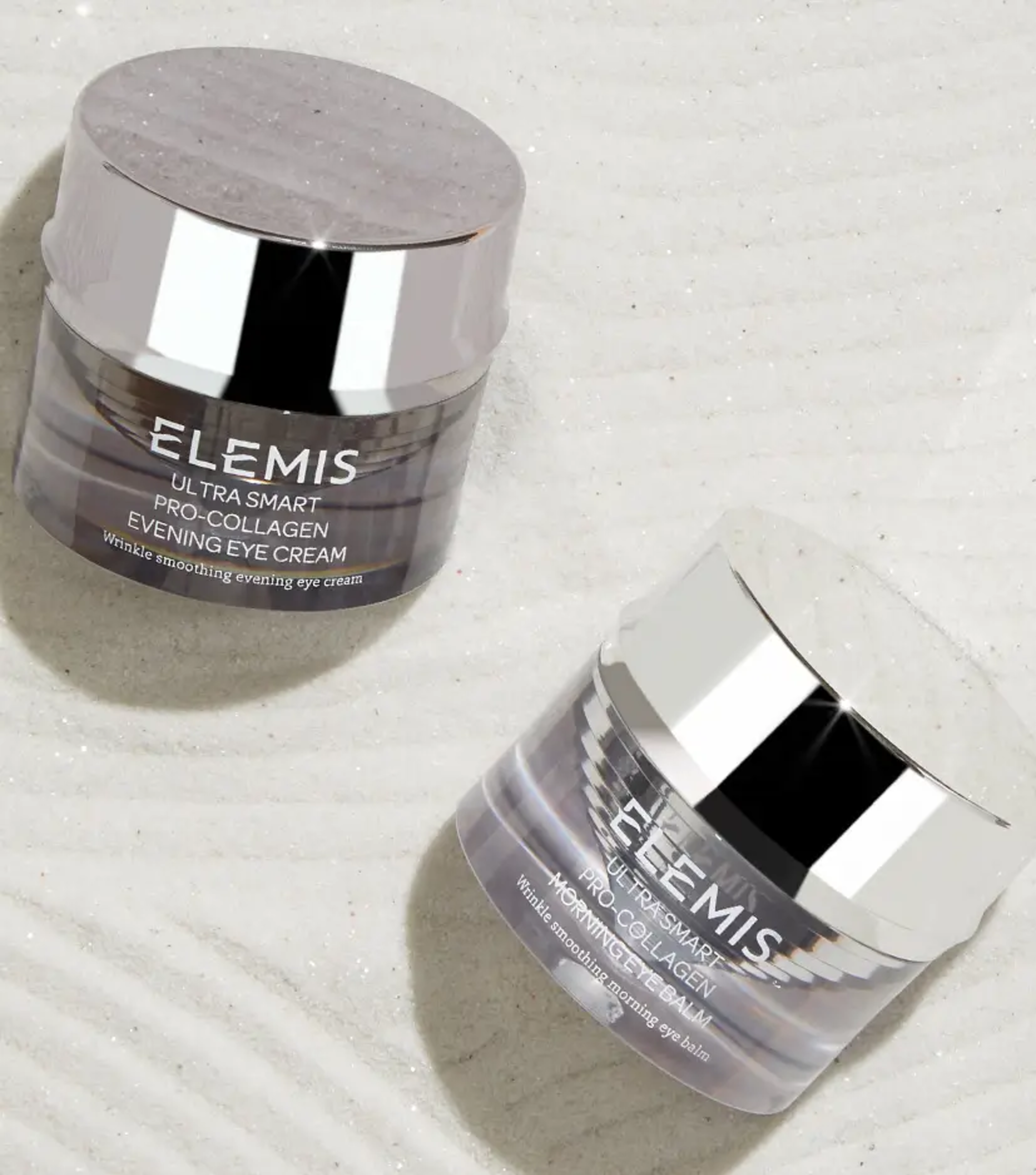 Two Elemis Ultra Smart Pro-Collagen eye cream jars, one for morning and one for evening, on a glittery surface.