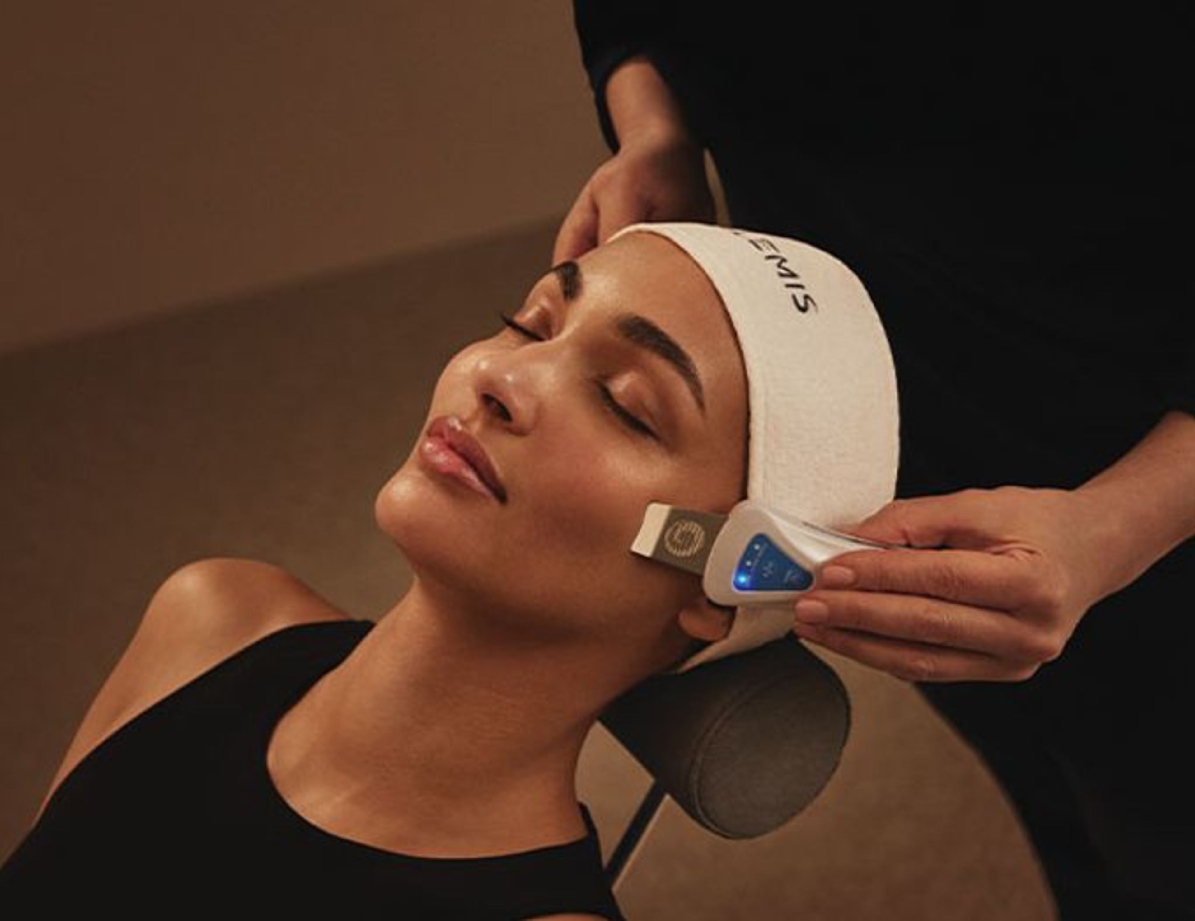 A person receiving a face mask applied with a wooden stick.