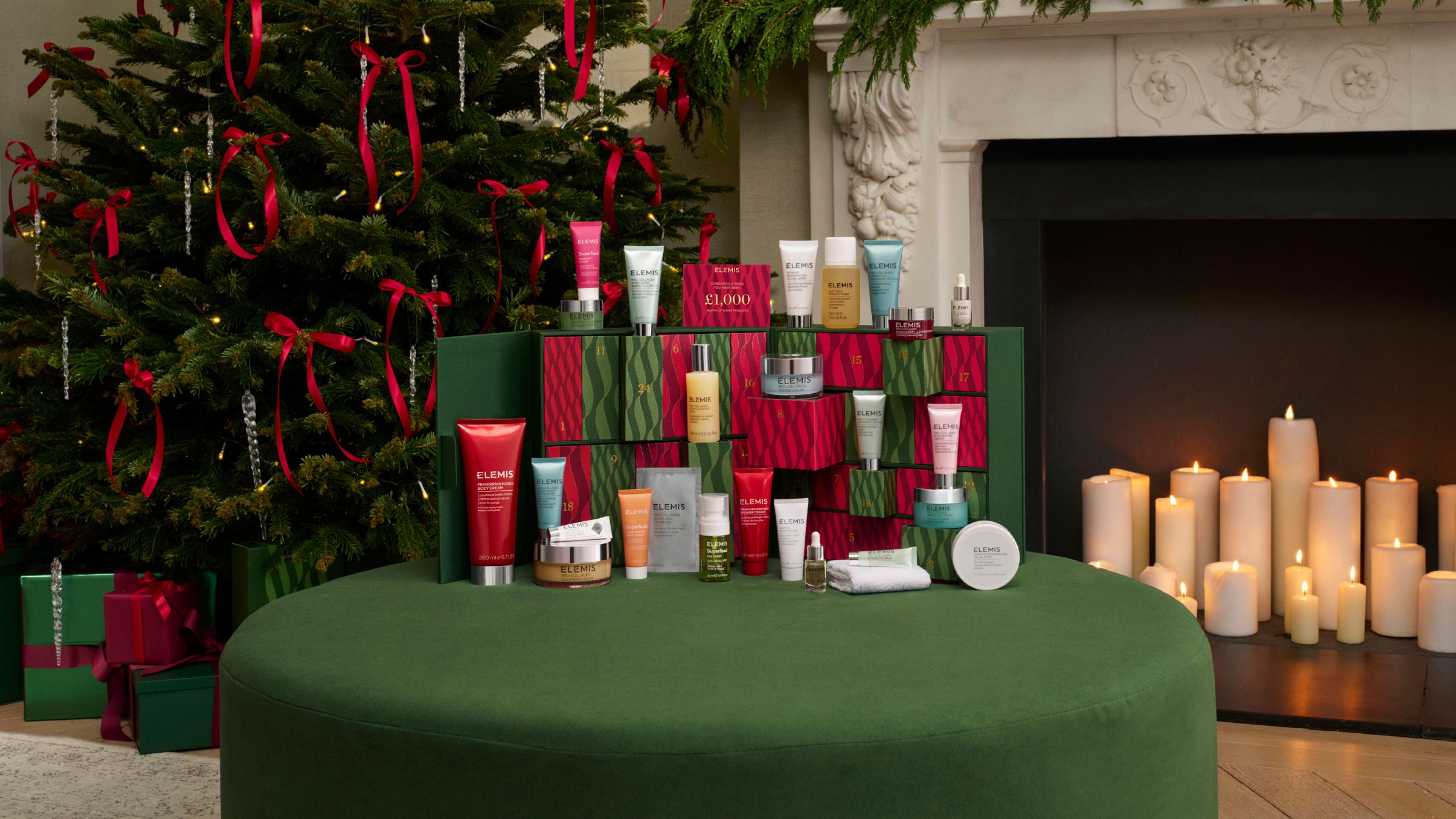 A hand holds an Elemis cleanser next to three other Elemis skincare products and a dark blue Elemis cosmetics bag.