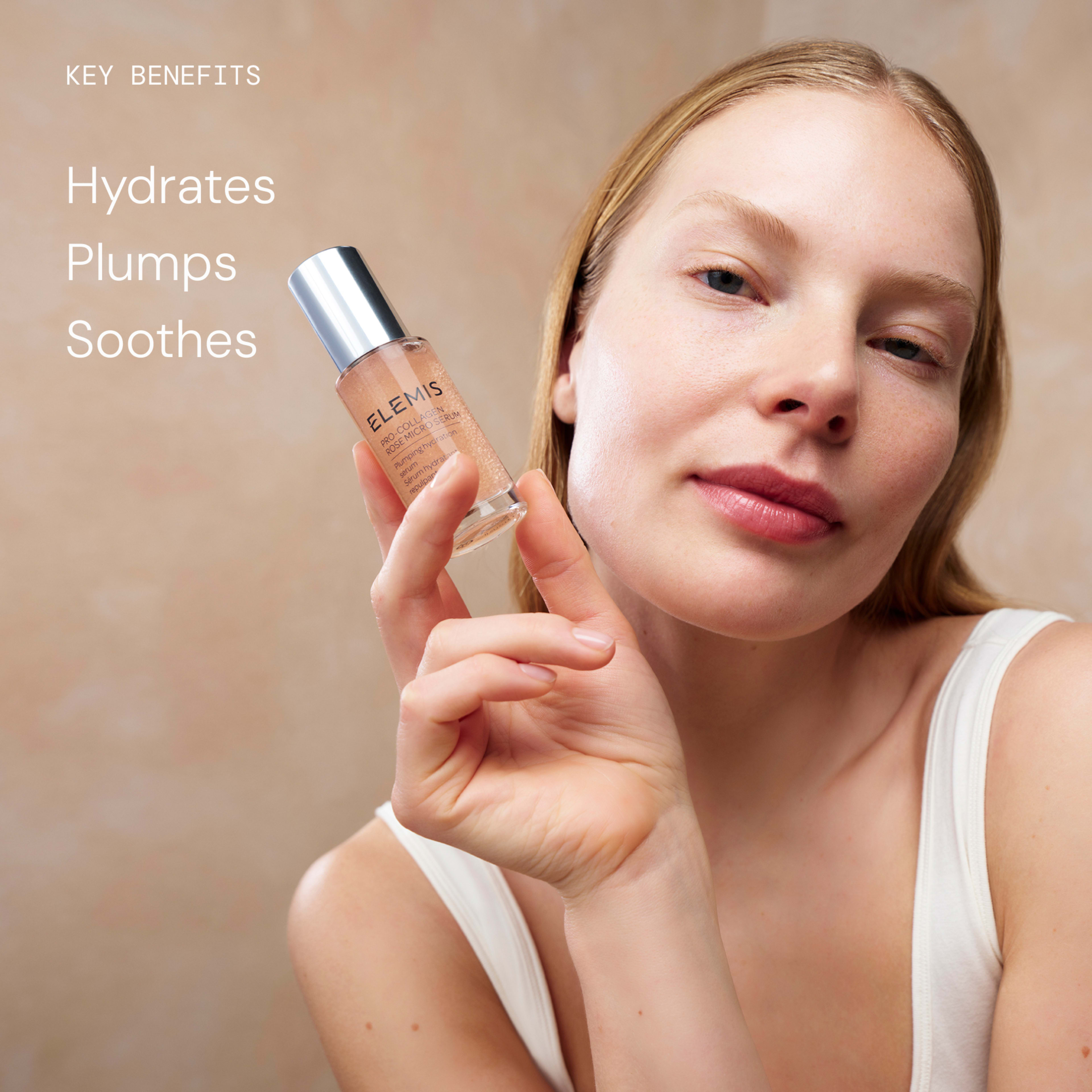 Woman with bare, glowing skin holds a bottle of ELEMIS serum close to her face against a soft neutral background. On the left, text reads “Key benefits: Hydrates, Plumps, Soothes”, promoting the skincare product’s effects.