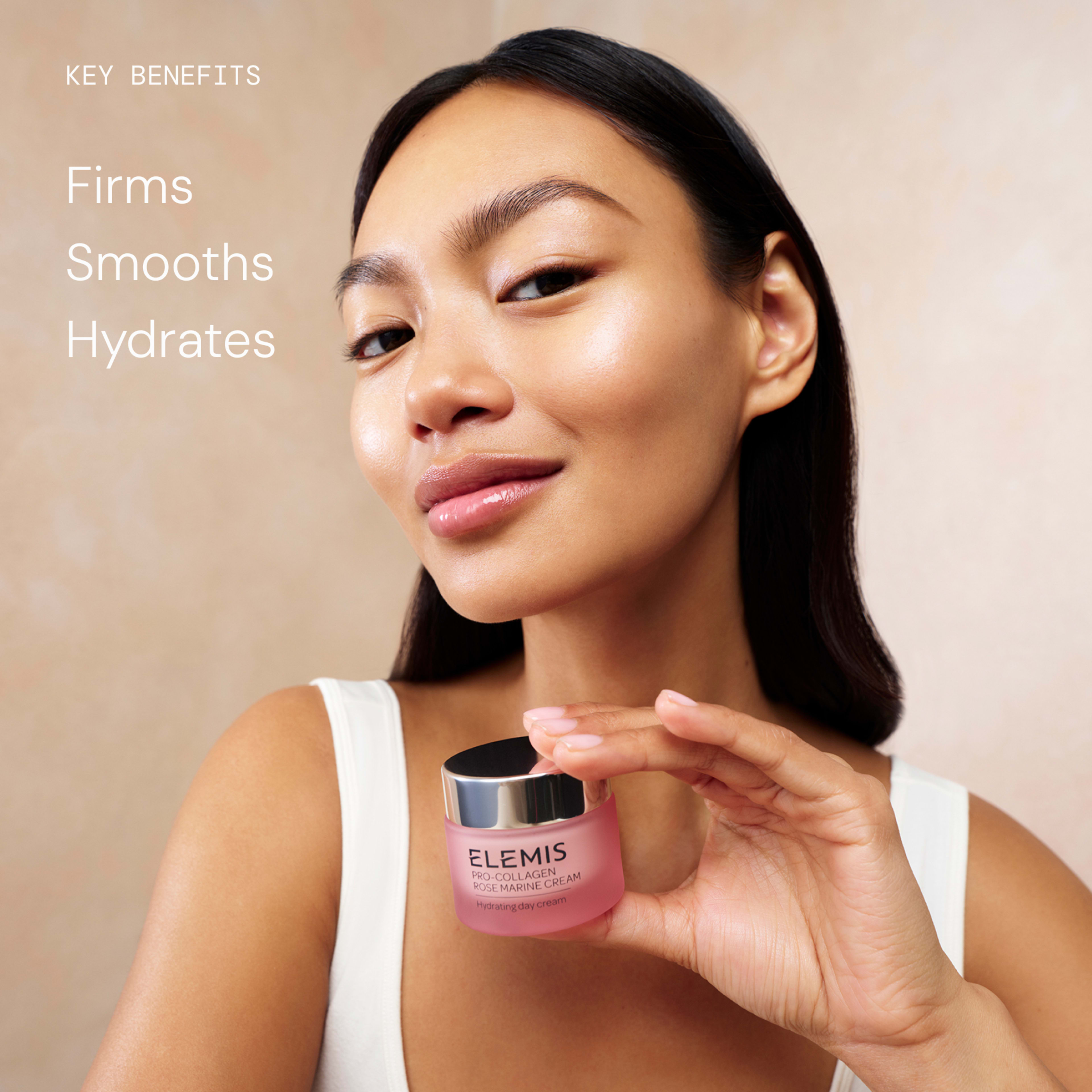 Woman with glowing skin holds a pink jar of ELEMIS Pro-Collagen Rose Marine Cream towards the camera, smiling slightly. Text on the left reads: "Key benefits: Firms, Smooths, Hydrates".
