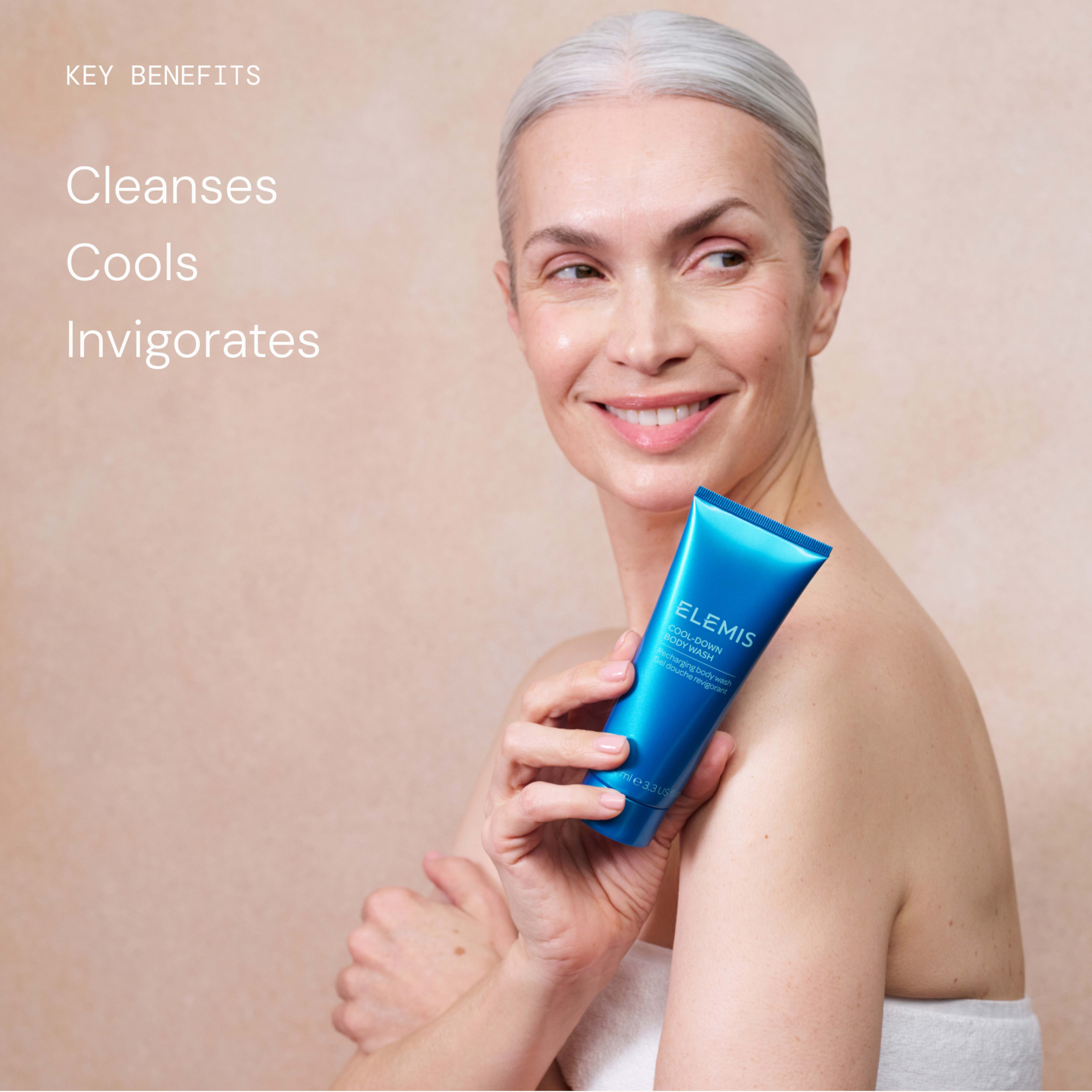 Smiling woman wrapped in a towel holds a bright blue ELEMIS skincare tube against a neutral background. On the left, text reads: “Key benefits: Cleanses, Cools, Invigorates.”