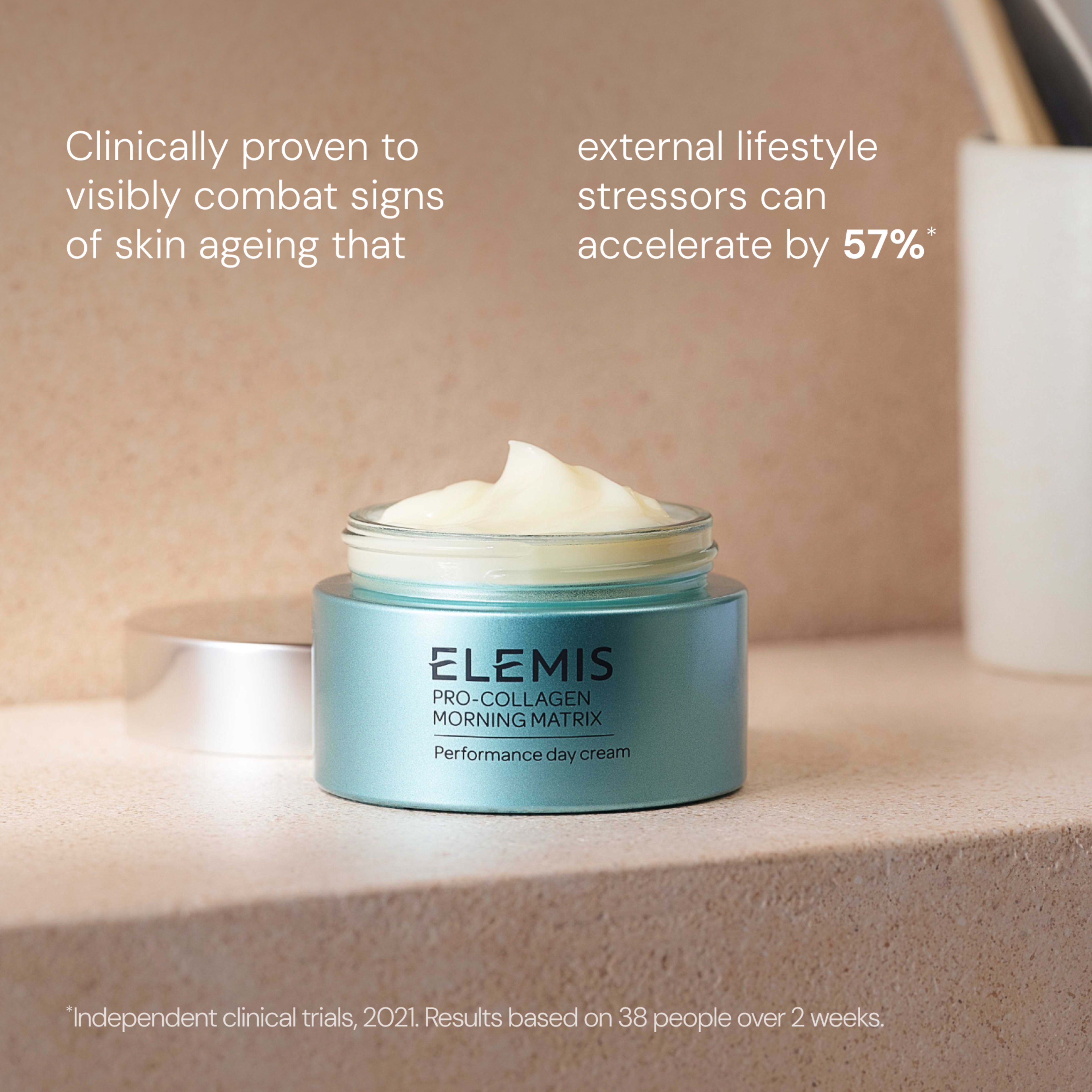 Open turquoise jar of ELEMIS Pro-Collagen Morning Matrix day cream with pale cream swatch on top, placed on a bathroom ledge. Text states it is clinically proven to visibly combat signs of skin ageing that external lifestyle stressors can accelerate by 57%.