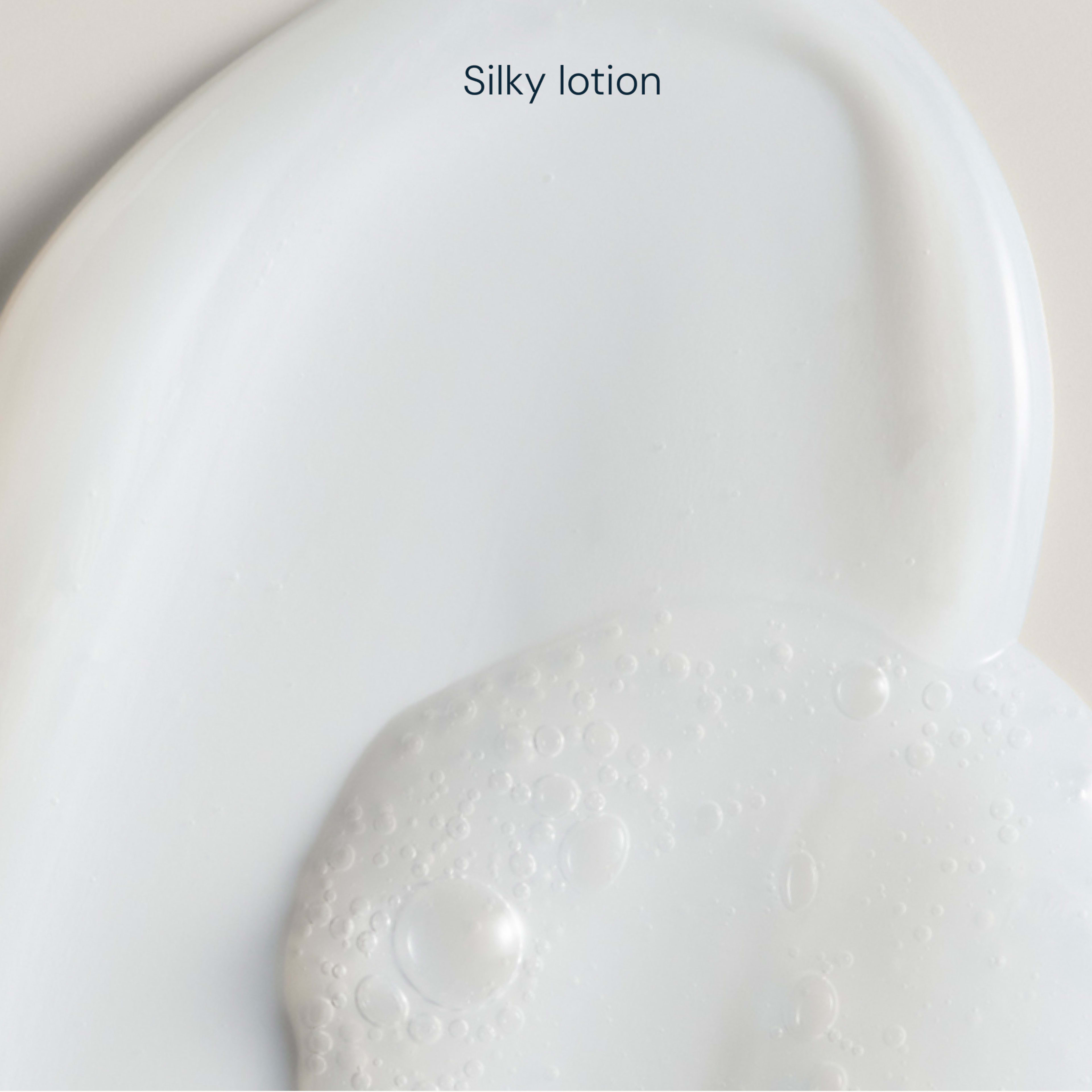 Close-up white skincare swatch labelled “Silky lotion”, showing smooth texture with small bubbles highlighting a lightweight, fluid consistency.
