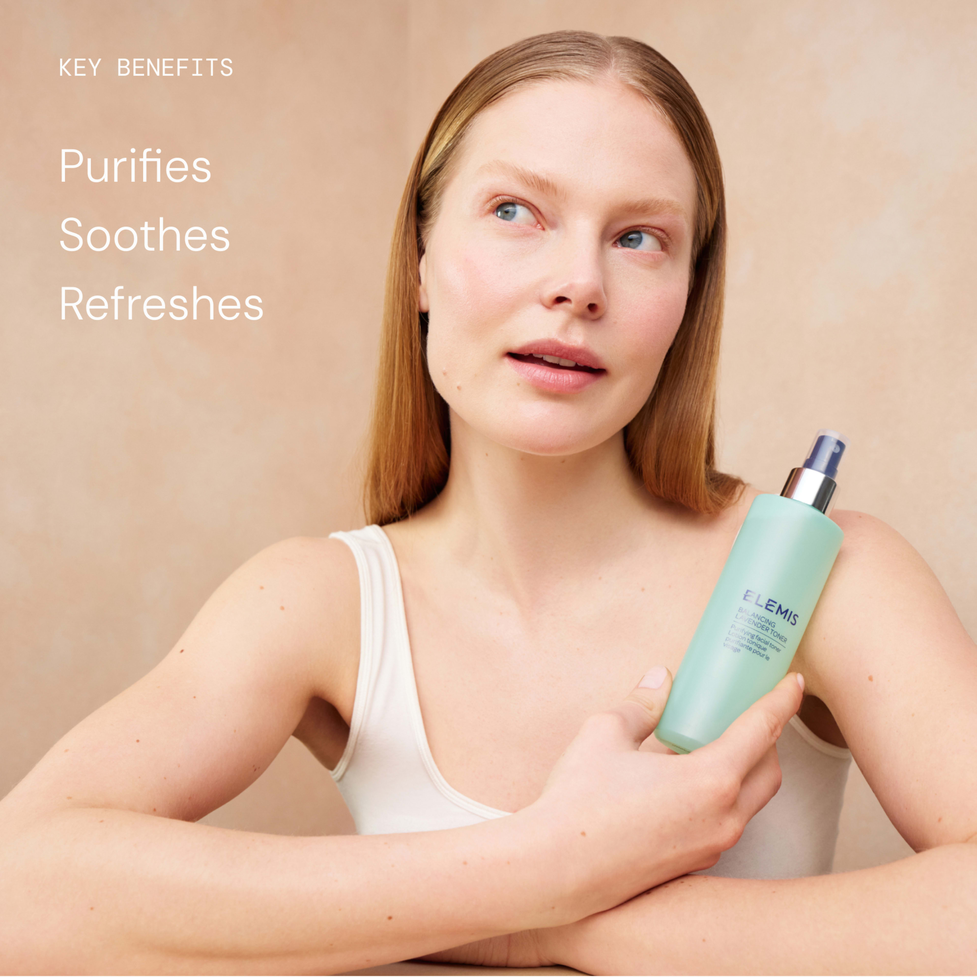 Woman with clear skin holding an ELEMIS facial mist bottle against a neutral background, looking upwards. On the left, white text reads: "Key benefits purifies, soothes, refreshes."