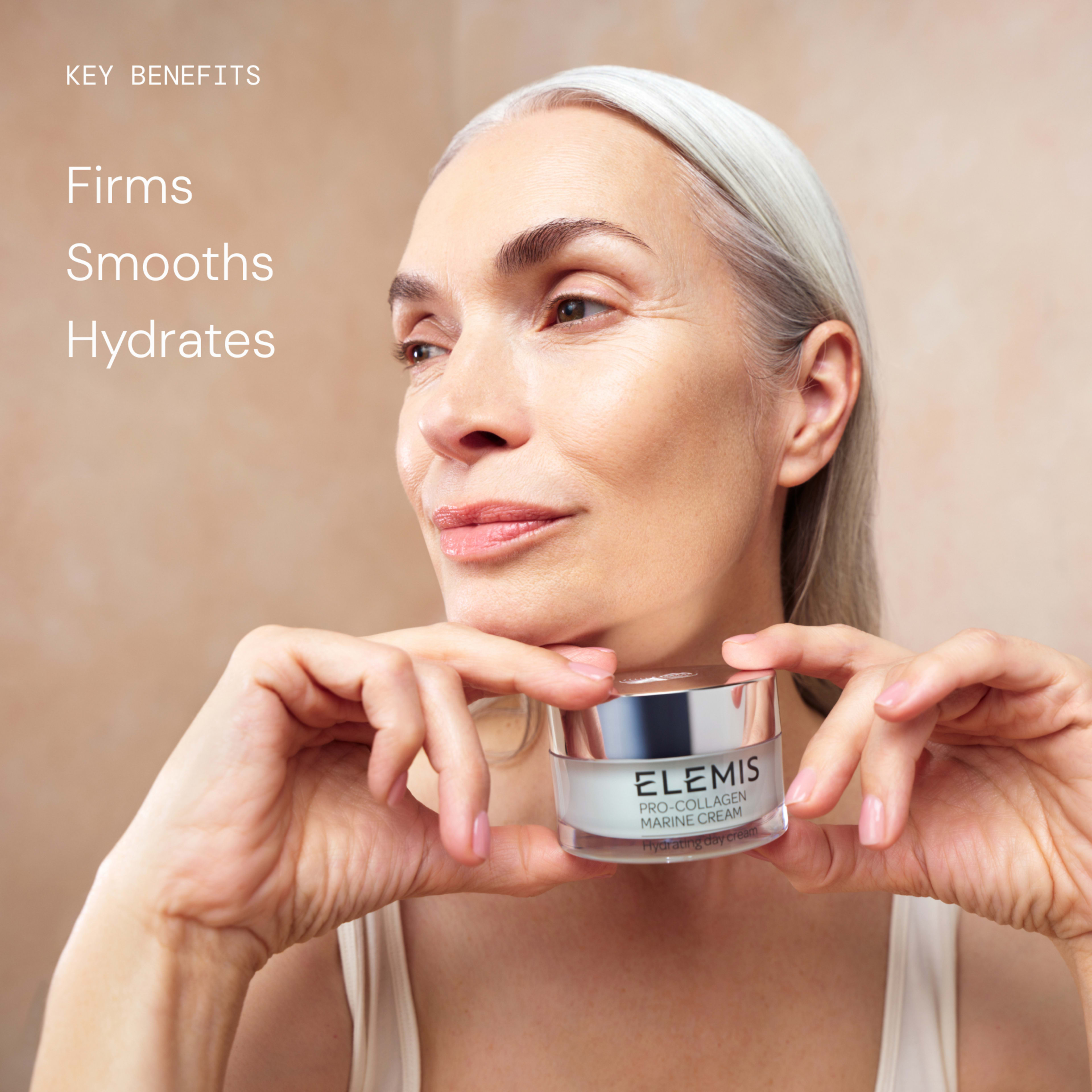 Smiling older woman with smooth, glowing skin holds a jar of ELEMIS Pro-Collagen Marine Cream in both hands. On the left, text reads: “Key benefits: Firms, Smooths, Hydrates.”
