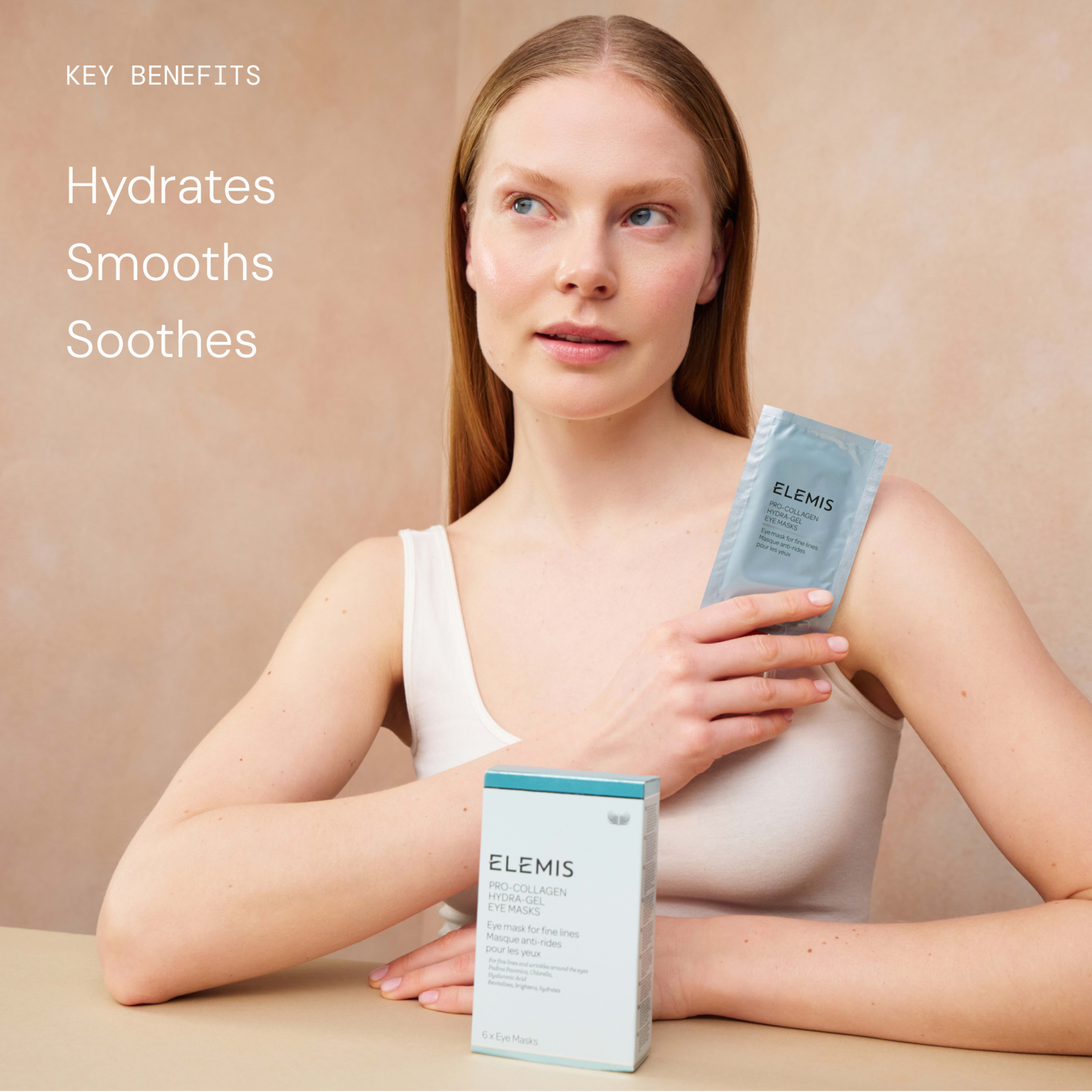 Woman in a beige vest sits at a table holding an ELEMIS Pro-Collagen Eye Mask sachet, with the product box resting by her arm. Text on the left reads: “Key benefits Hydrates Smooths Soothes”.