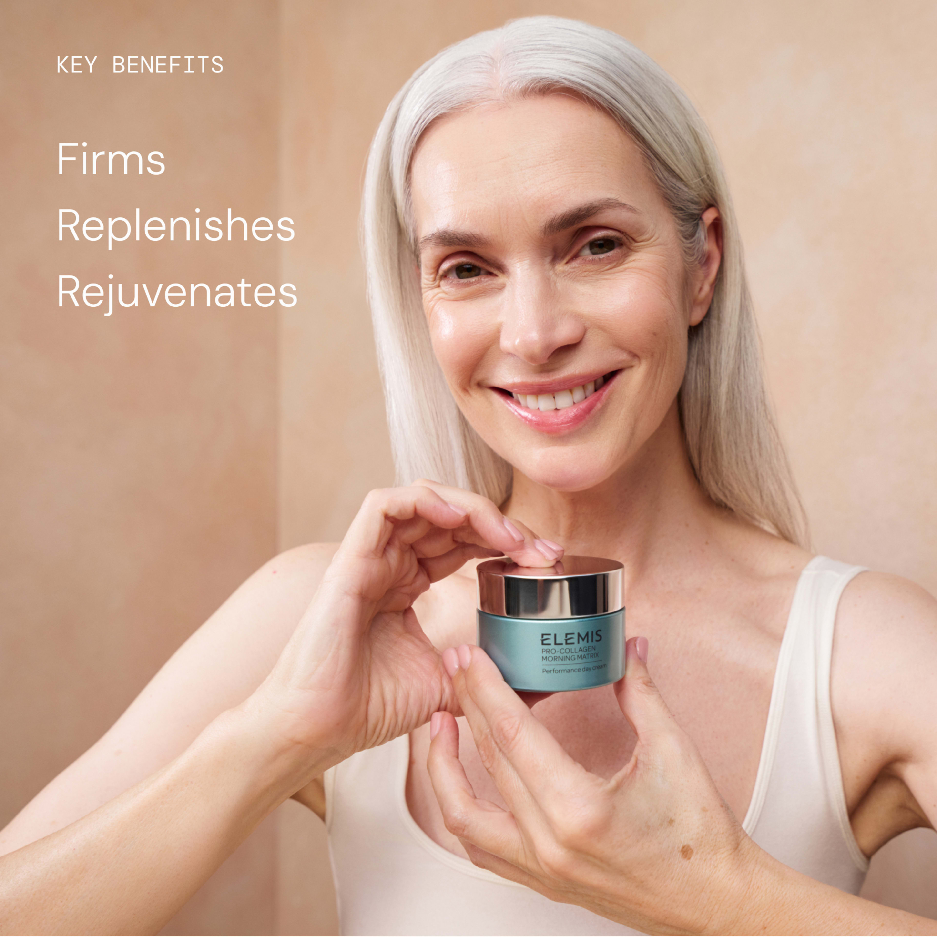 Smiling woman with long grey hair holds a jar of ELEMIS Pro-Collagen Marine Cream towards the camera. On the left, text reads: “Key benefits: firms, replenishes, rejuvenates.”