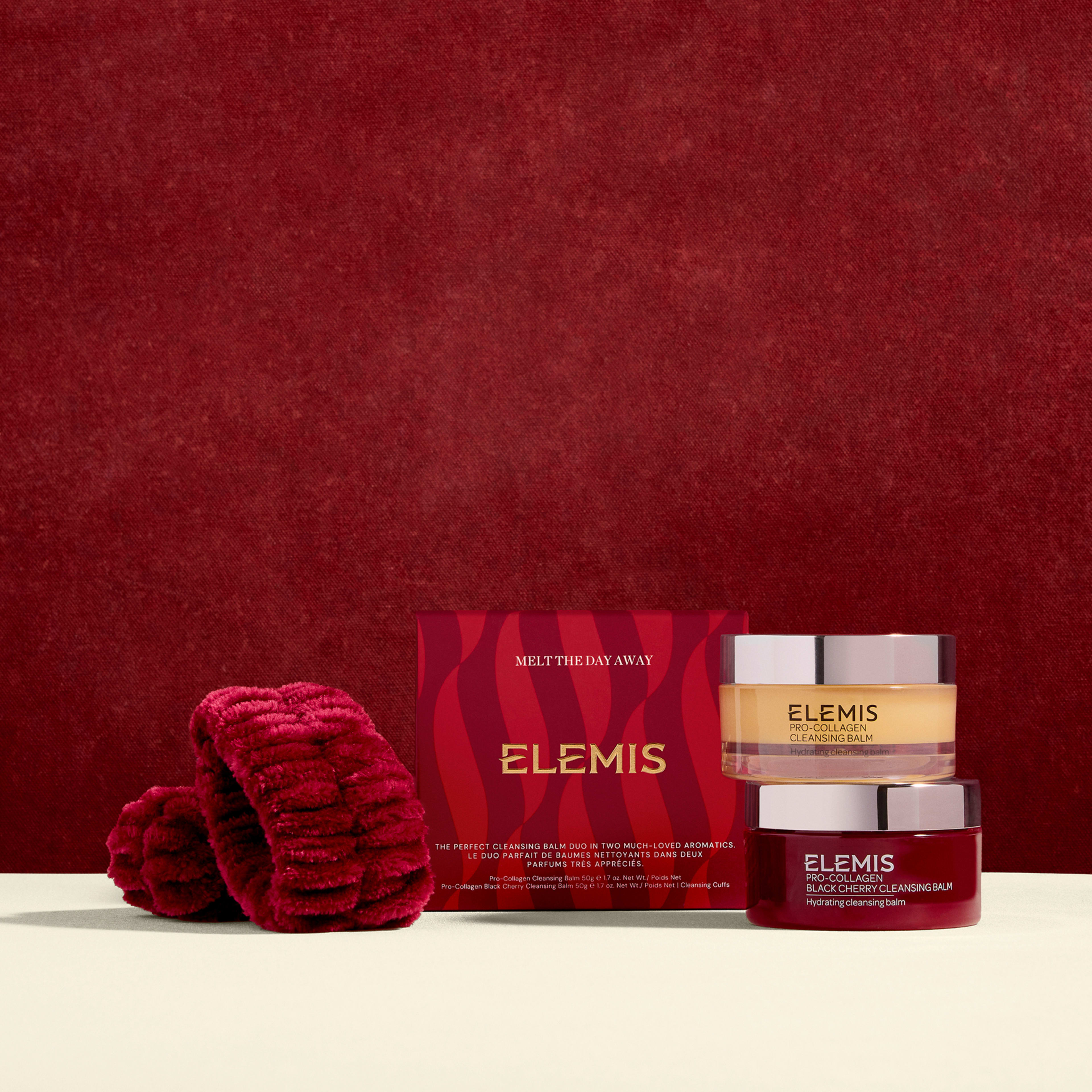 ELEMIS Melt The Day Away gift set against a deep red background, featuring a red box, a red headband and two cleansing balms in stacked jars: Pro-Collagen Cleansing Balm and a red-branded black cherry cleansing balm.