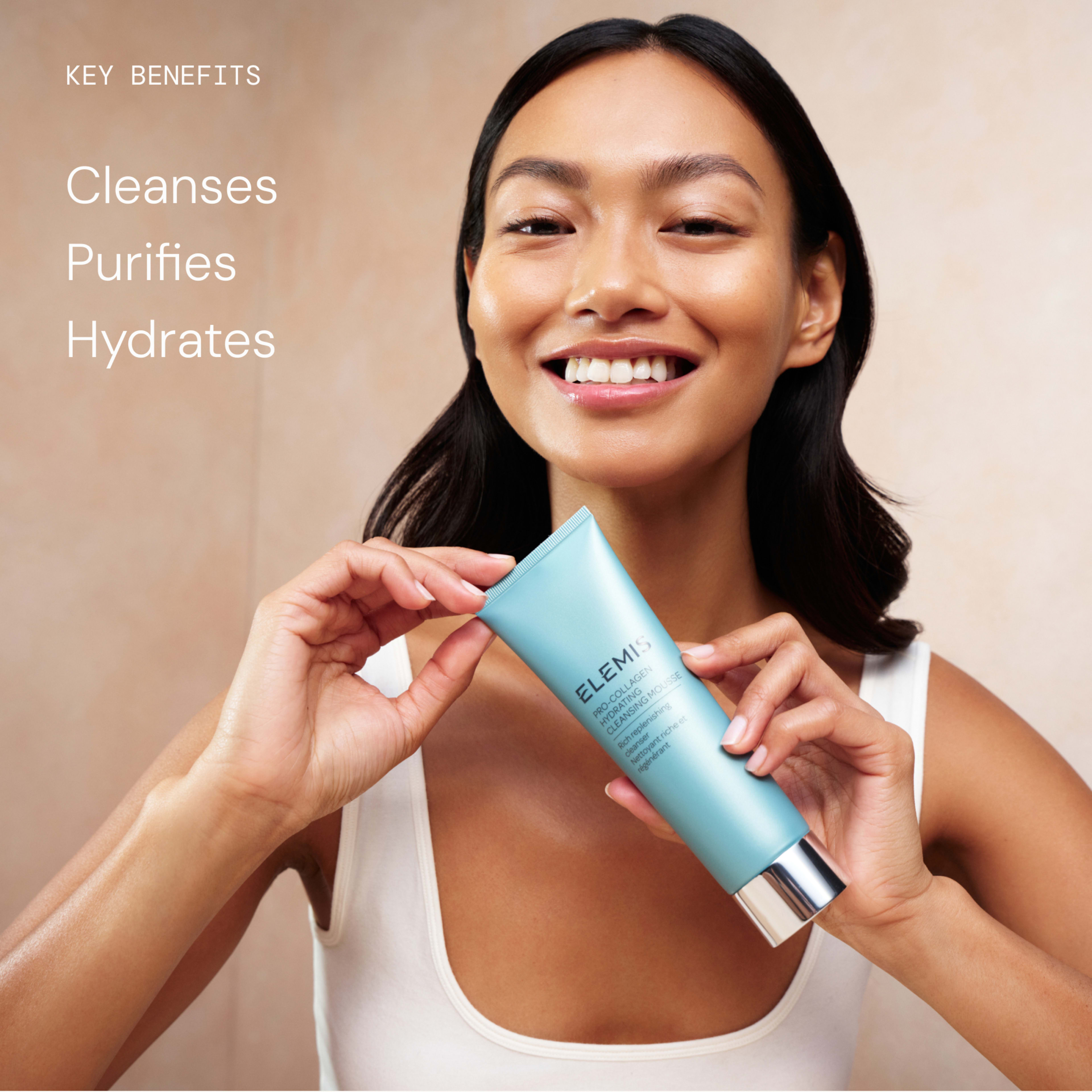 Smiling woman holding a tube of ELEMIS cleanser towards the camera against a neutral background. On the left, text reads: "Key benefits cleanses, purifies, hydrates."