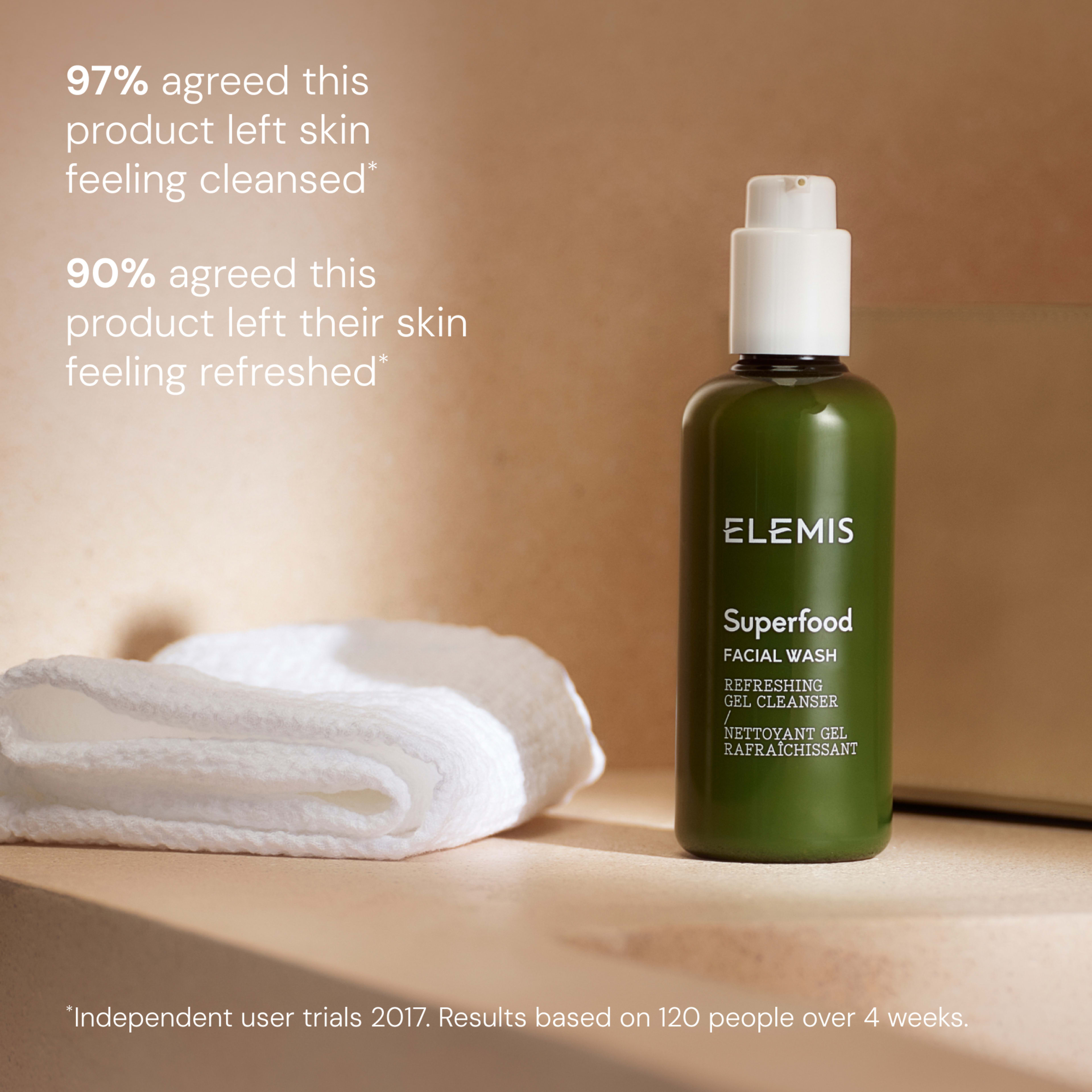 ELEMIS Superfood Facial Wash bottle on a bathroom surface beside a folded white cloth, with text stating “97% agreed this product left skin feeling cleansed” and “90% agreed this product left their skin feeling refreshed”, plus small print on trial results.