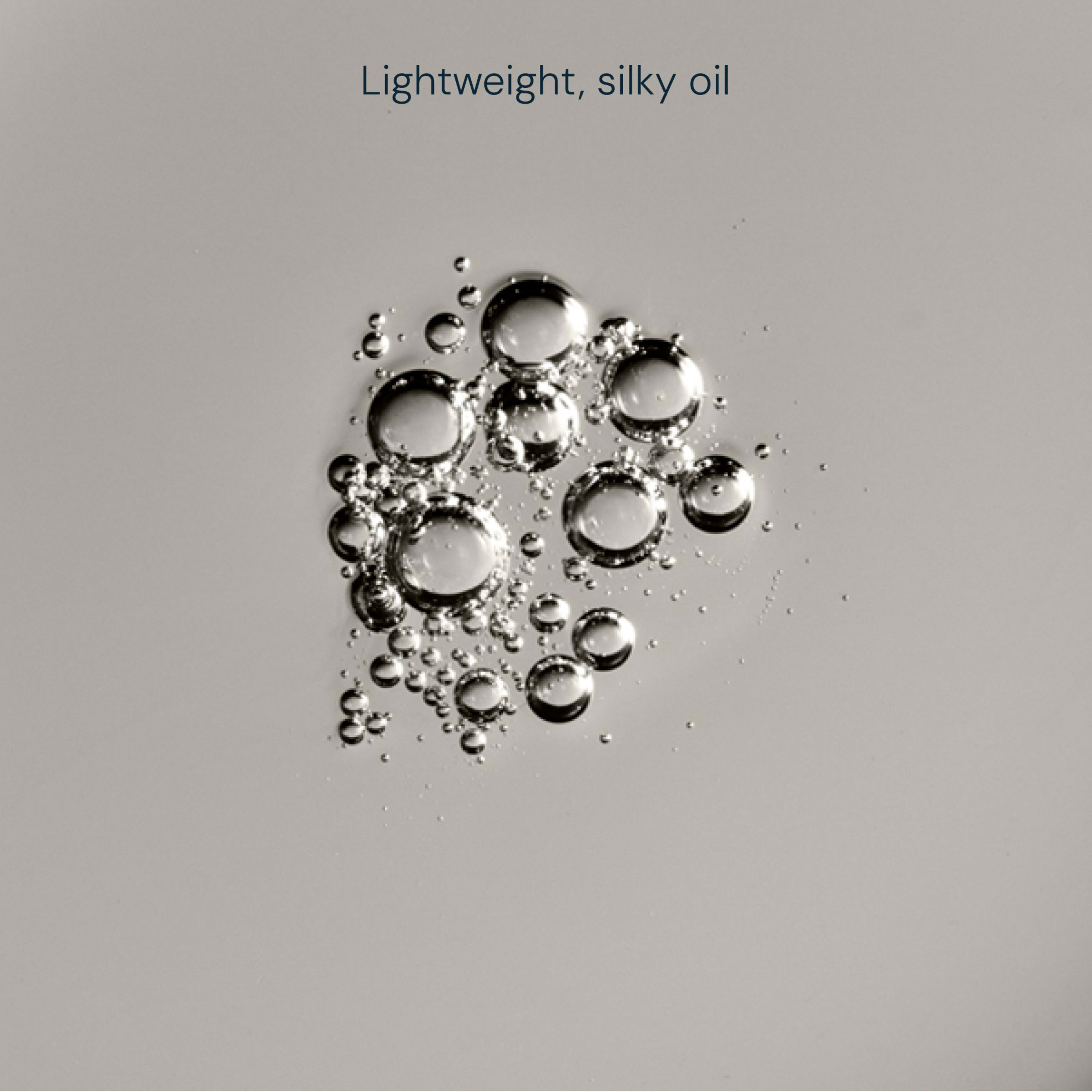 Clear droplets of lightweight, silky oil pooled on a smooth, pale surface, with the phrase “Lightweight, silky oil” above.