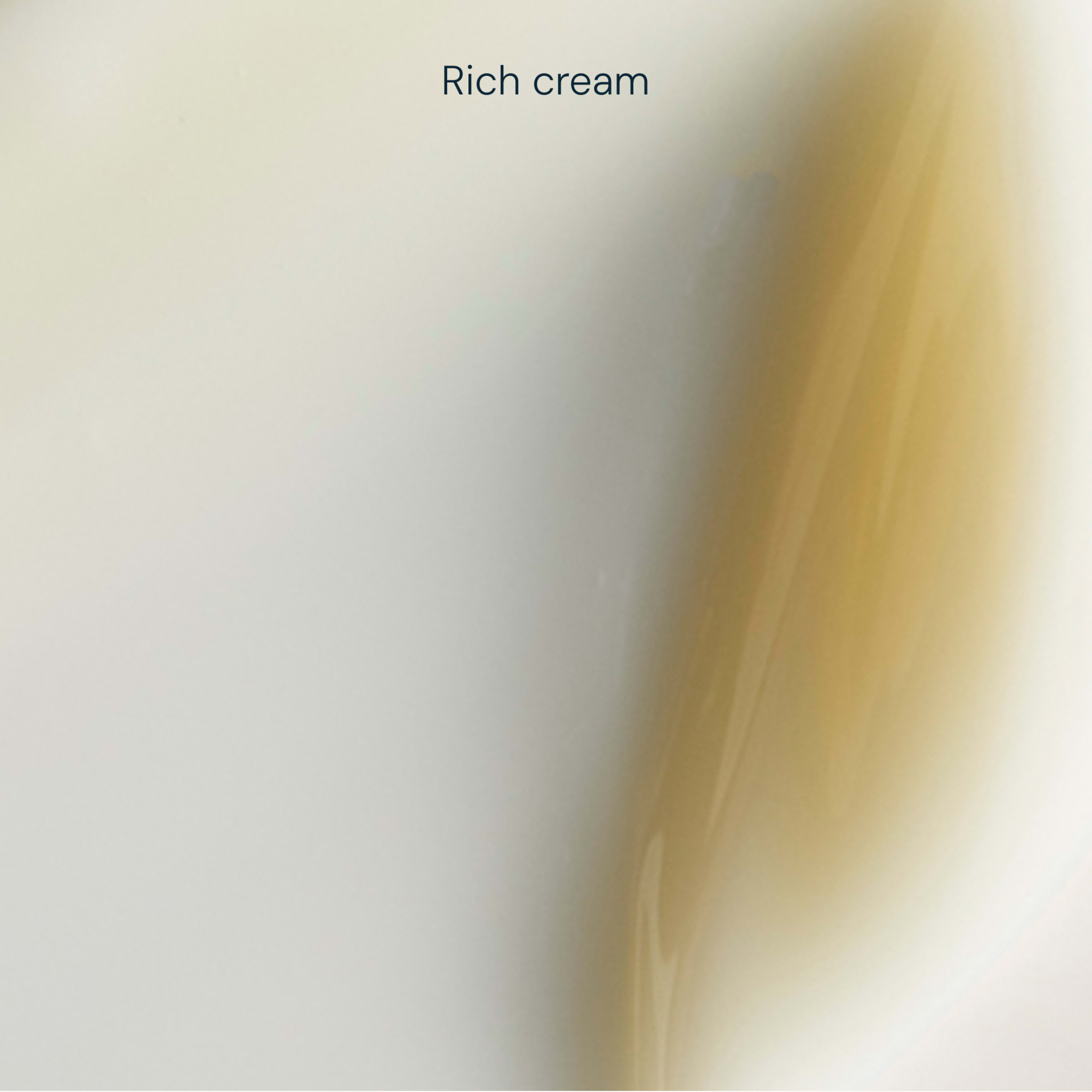 Close-up of a smooth, off-white rich cream texture with a soft golden swatch on the right, overlaid with the words "Rich cream" near the top.
