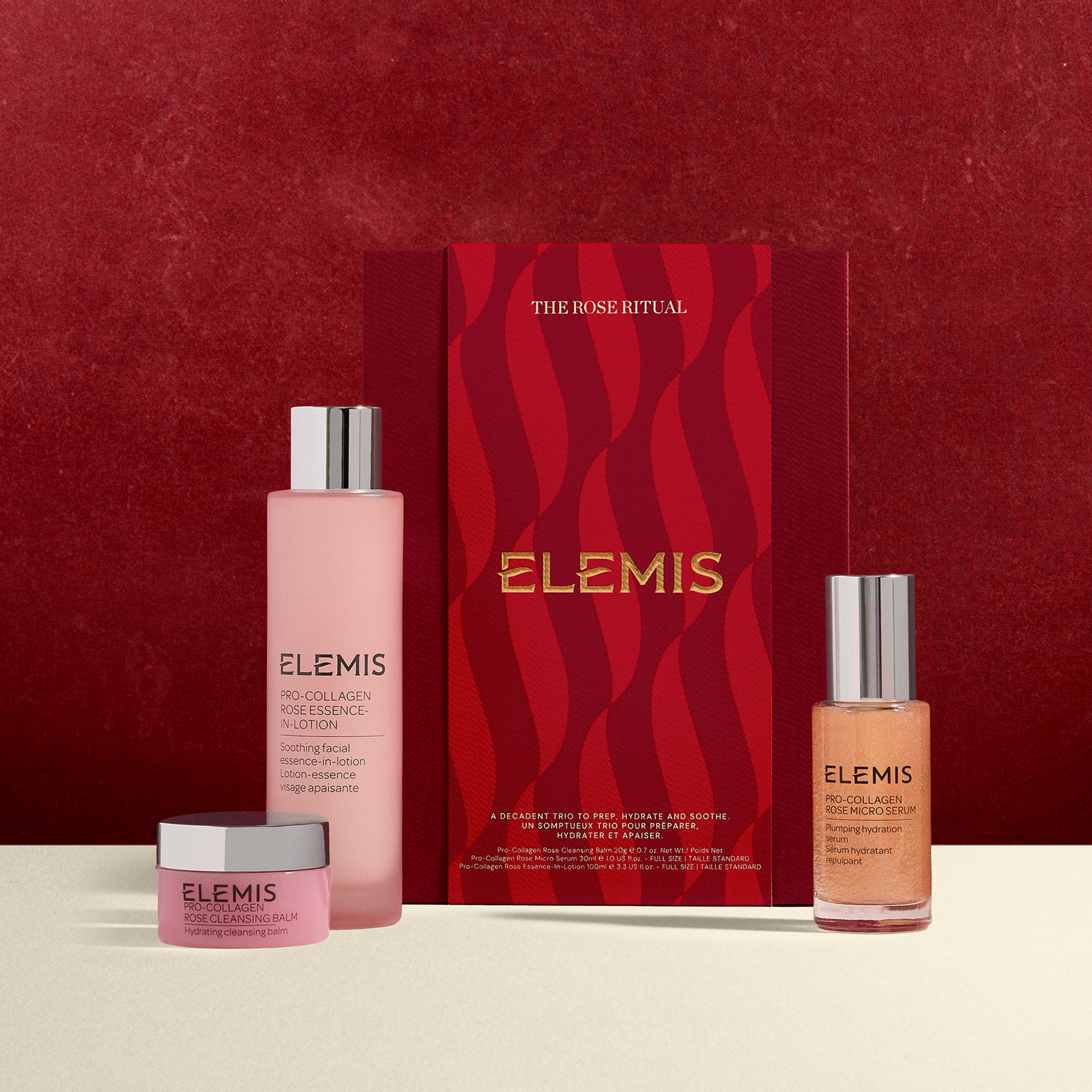 ELEMIS The Rose Ritual gift set against a red background, featuring Pro-Collagen rose cleansing balm, Pro-Collagen rose essence lotion and Pro-Collagen rose facial oil in pink and rose-gold packaging.