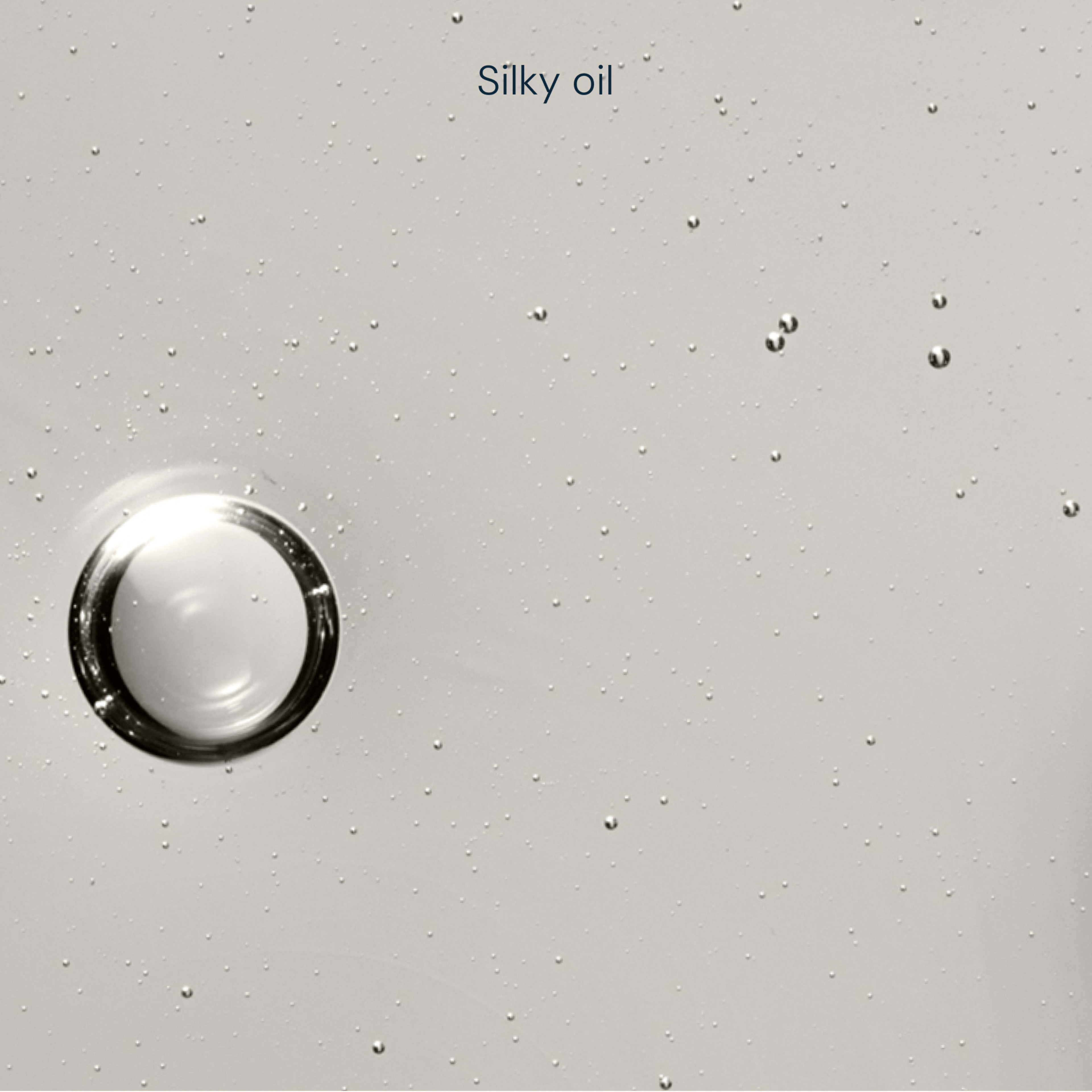 Clear, pale silky oil texture with a single large droplet and many tiny suspended bubbles against a light background, with the words “Silky oil” at the top.