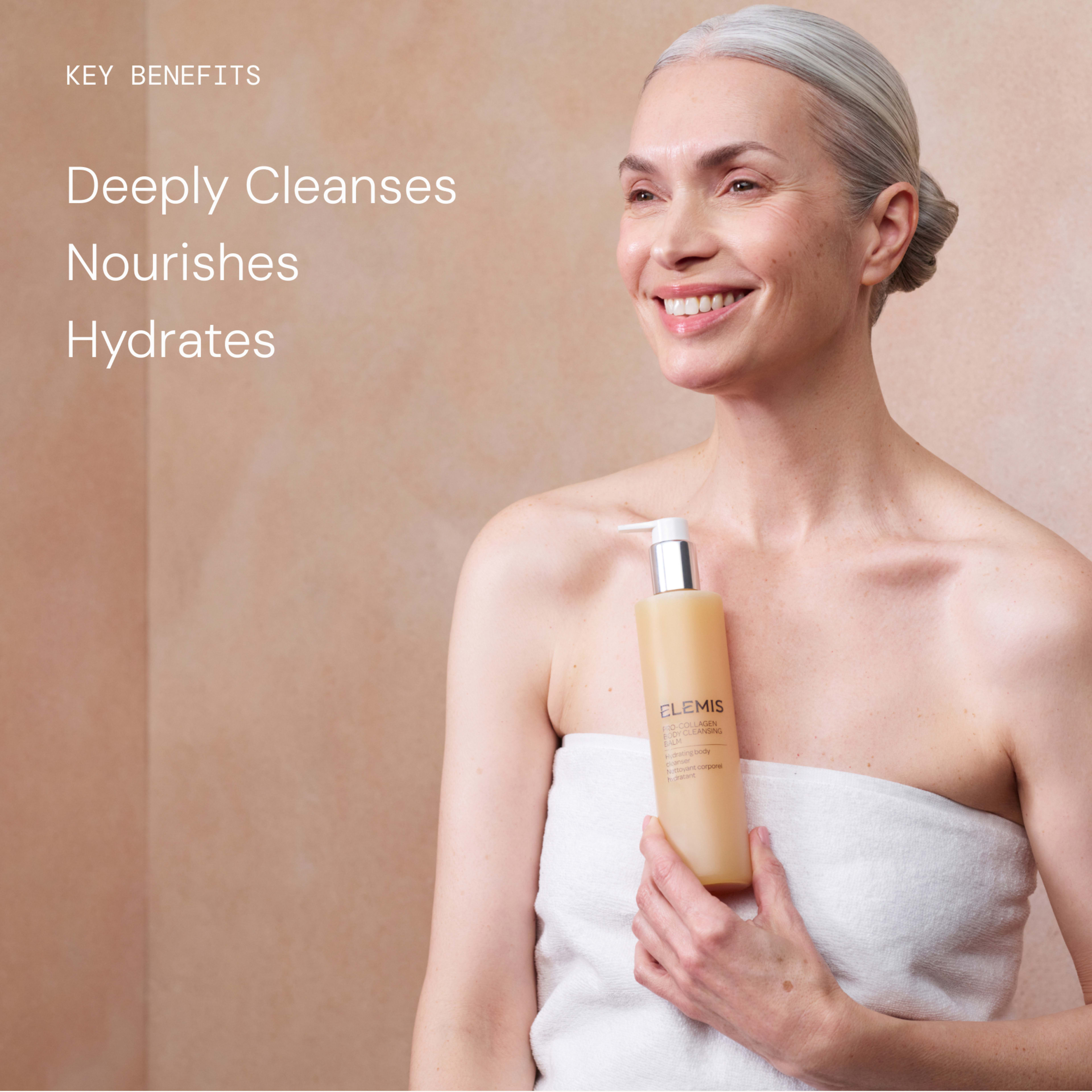 Smiling woman wrapped in a towel holds an ELEMIS bottle against a soft beige background. On the left, text reads: "KEY BENEFITS" followed by "Deeply Cleanses", "Nourishes", "Hydrates".
