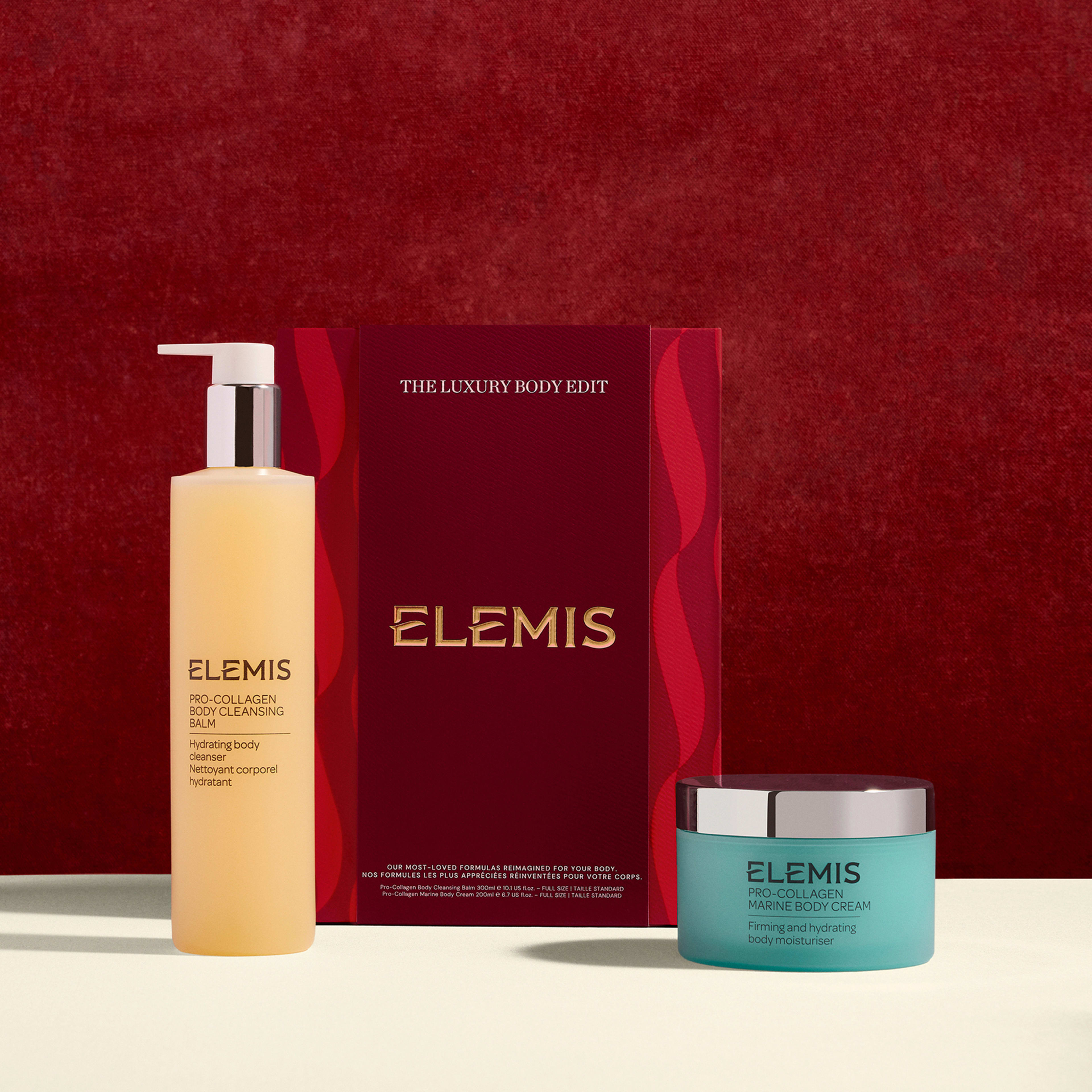 ELEMIS The Luxury Body Edit gift set against a red background, featuring a tall Pro-Collagen Body Cleansing Balm bottle and a turquoise Pro-Collagen Firming Body Cream jar arranged in front of the red and gold presentation box.