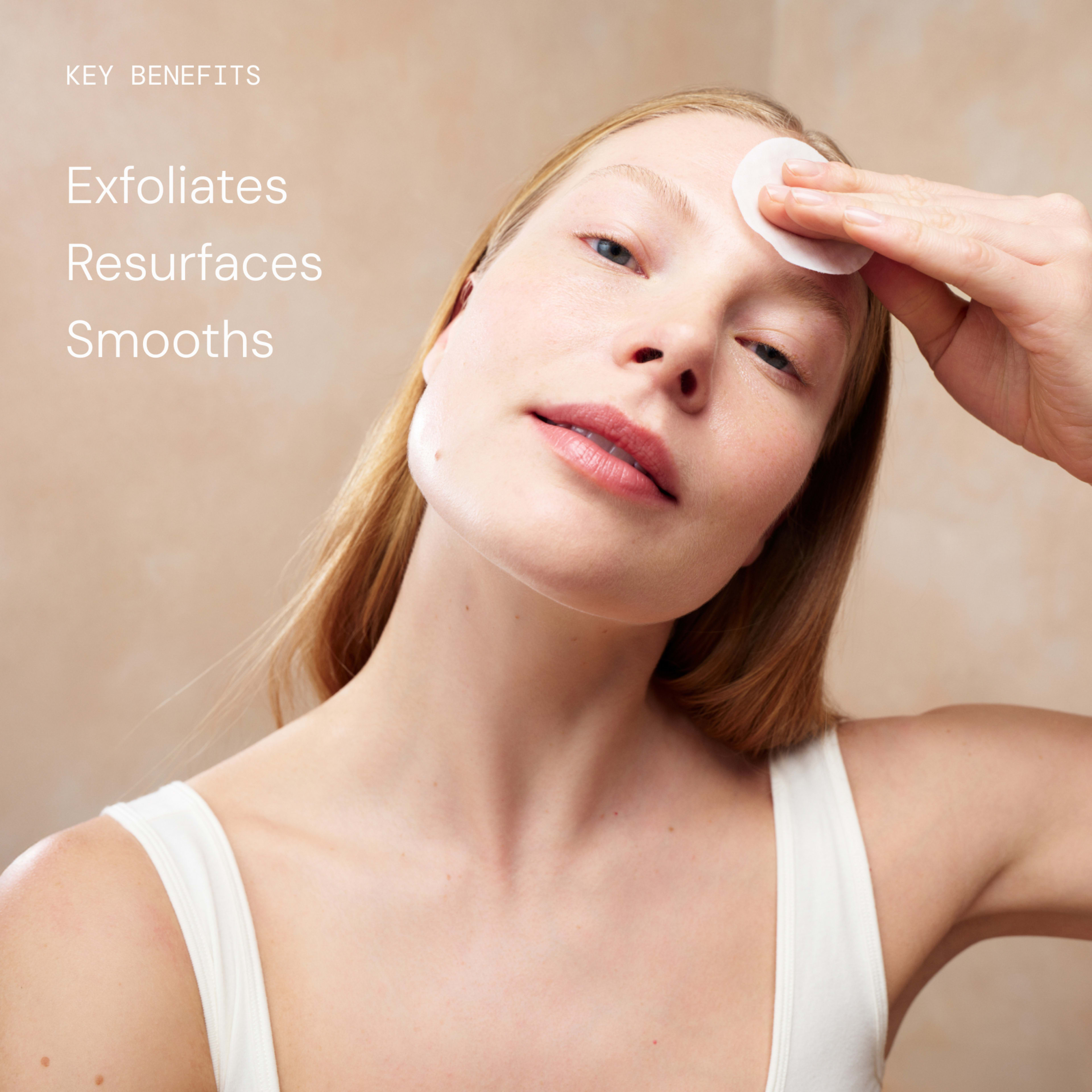 Woman in a white vest gently applies skincare with a cotton pad to her forehead, showing smooth, glowing skin. On the left, text reads: "Key benefits: Exfoliates, Resurfaces, Smooths".