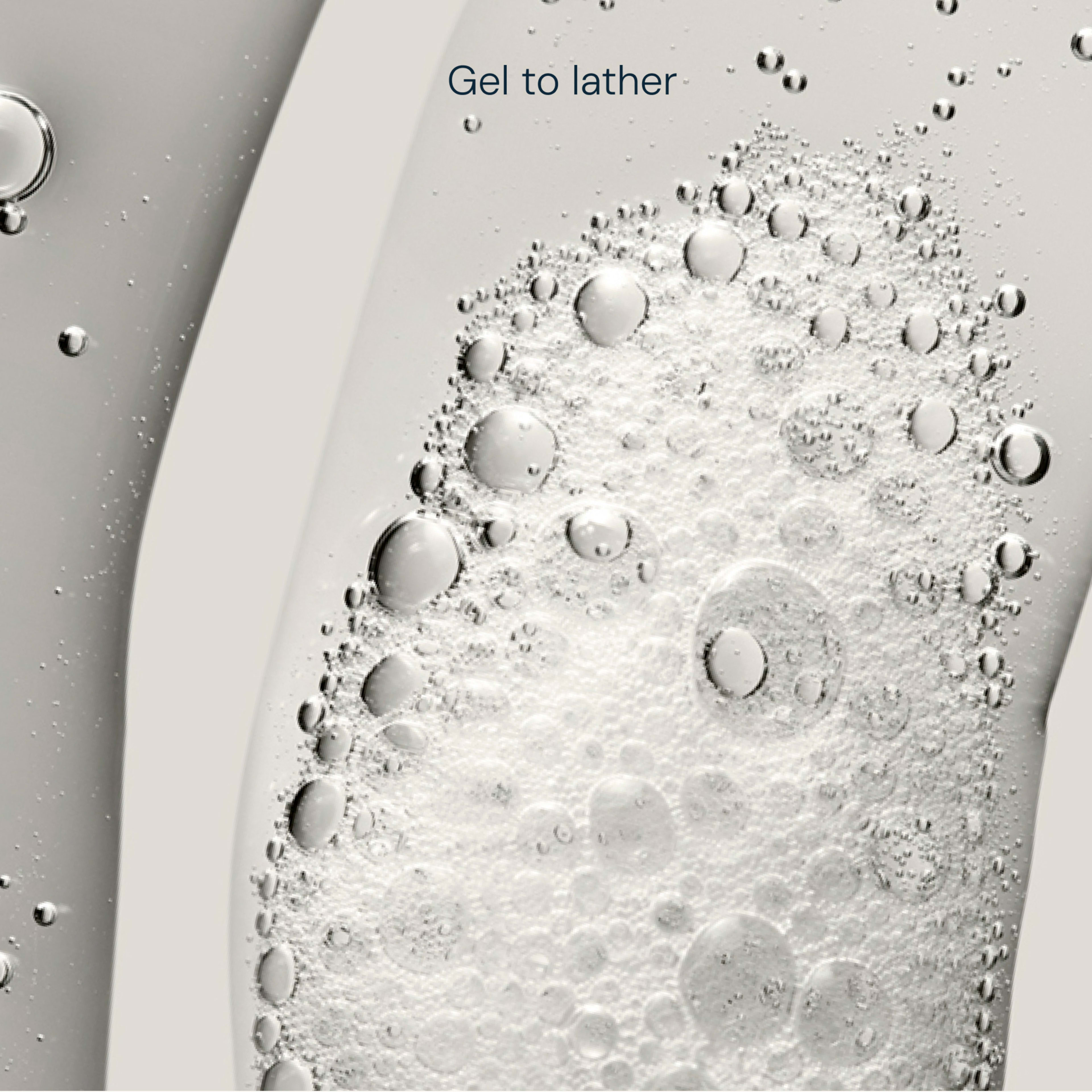 Close-up of clear cleansing gel transforming into white lather with bubbles, overlaid with the words "Gel to lather".