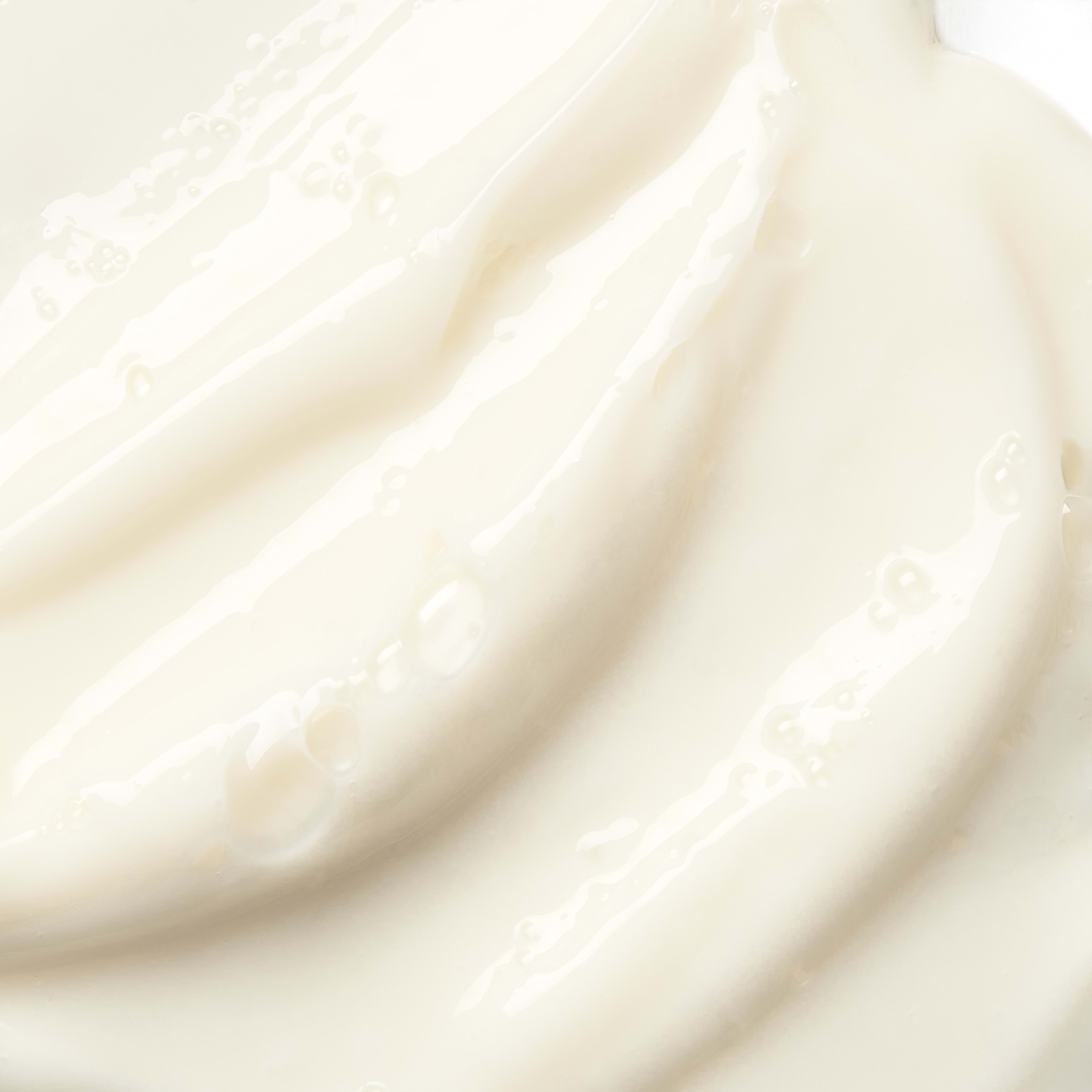 Close-up swatch of smooth, glossy white cream with soft waves and tiny surface bubbles.